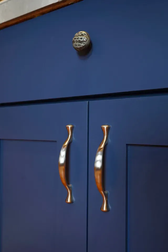 A close up of a blue cabinet with gold handles.