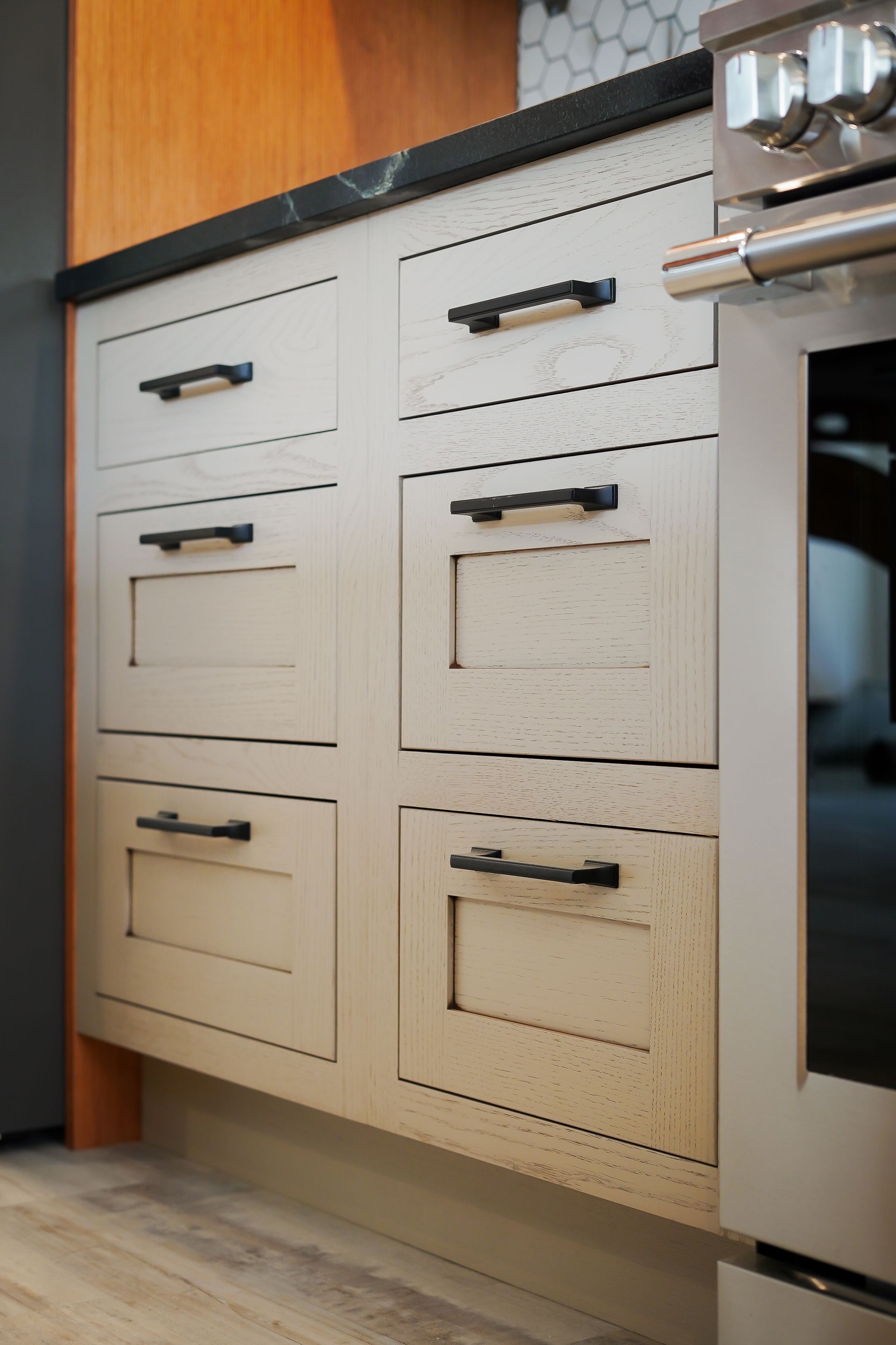A kitchen with white cabinets and black handles and a stove.