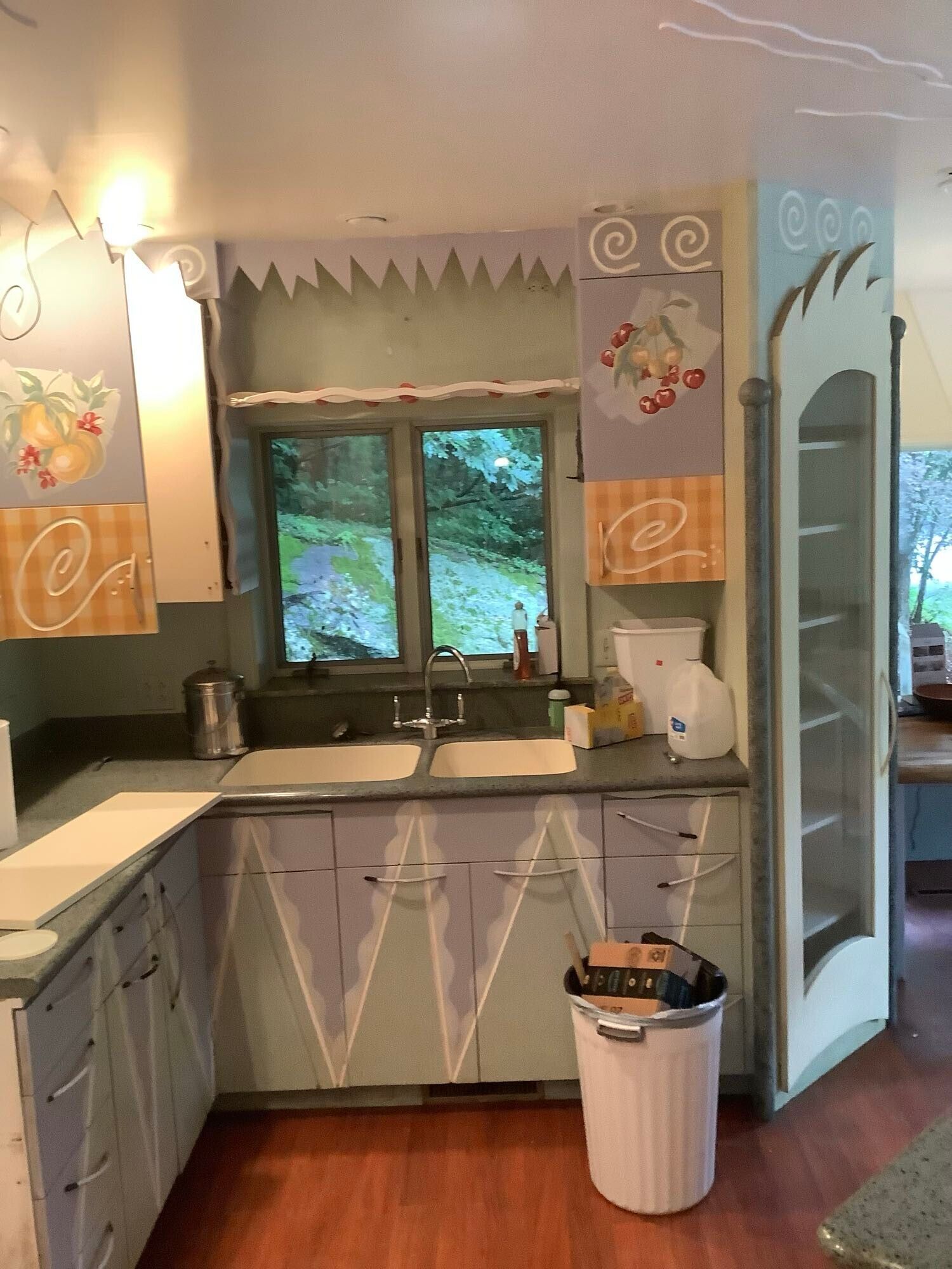 A kitchen with purple cabinets and a white trash can