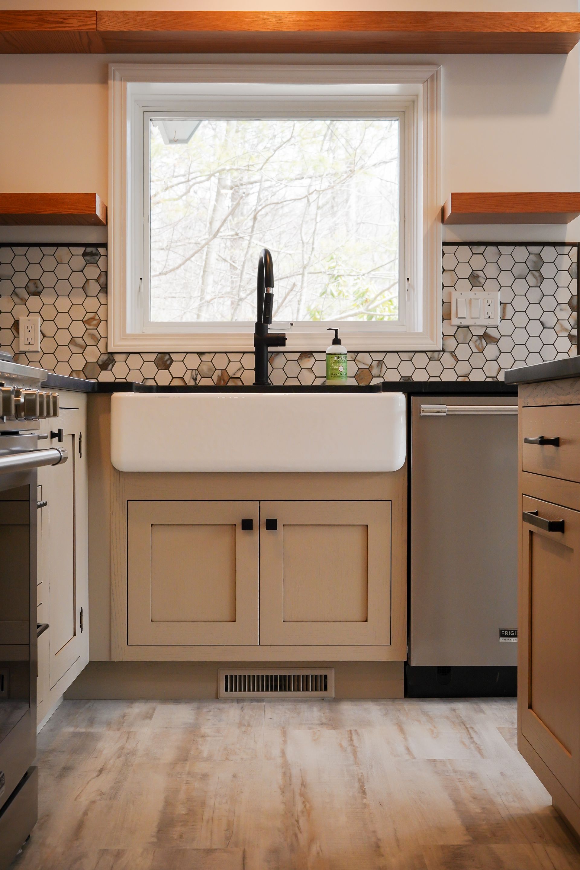 A kitchen with a white farmhouse sink and a window.