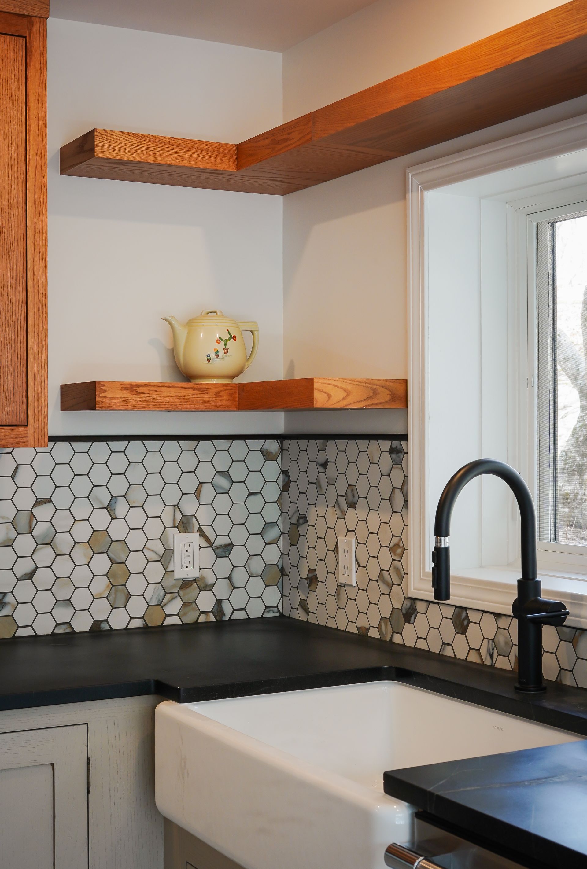 A kitchen with a sink , shelves , and a window.