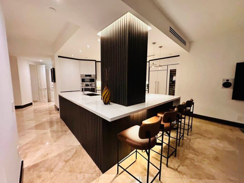 A kitchen with a large island and stools in it.