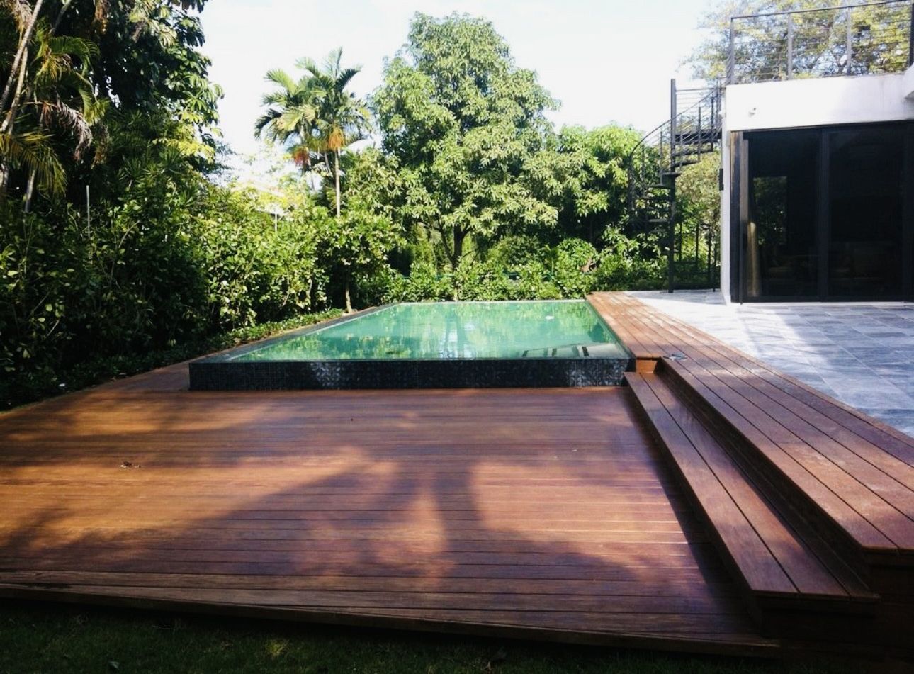 A wooden deck with a swimming pool in the background