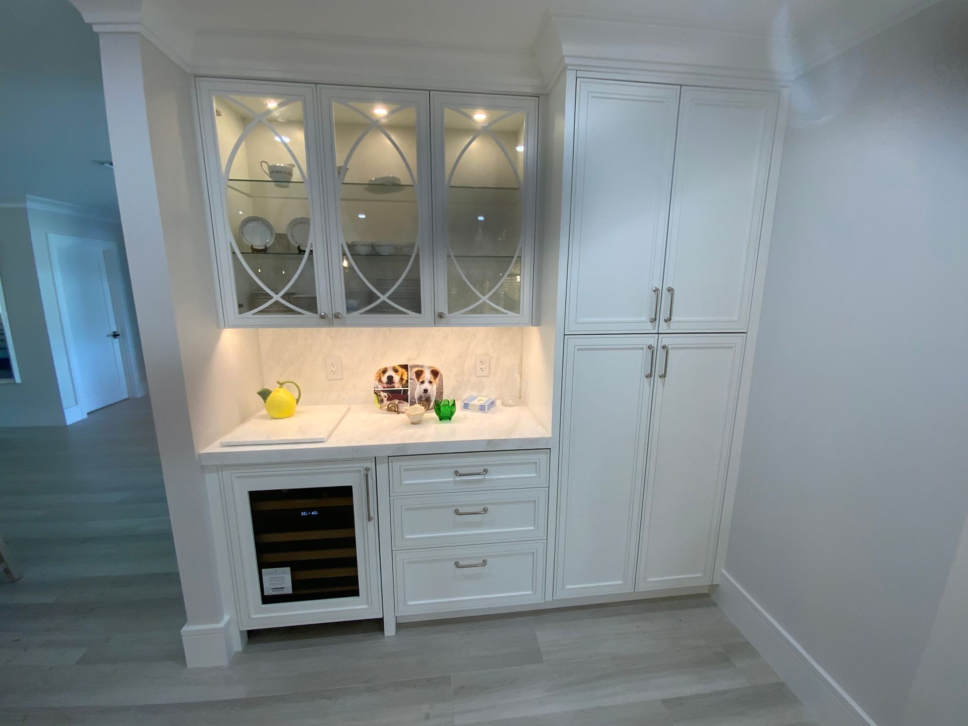 A kitchen with white cabinets and a wine cooler.
