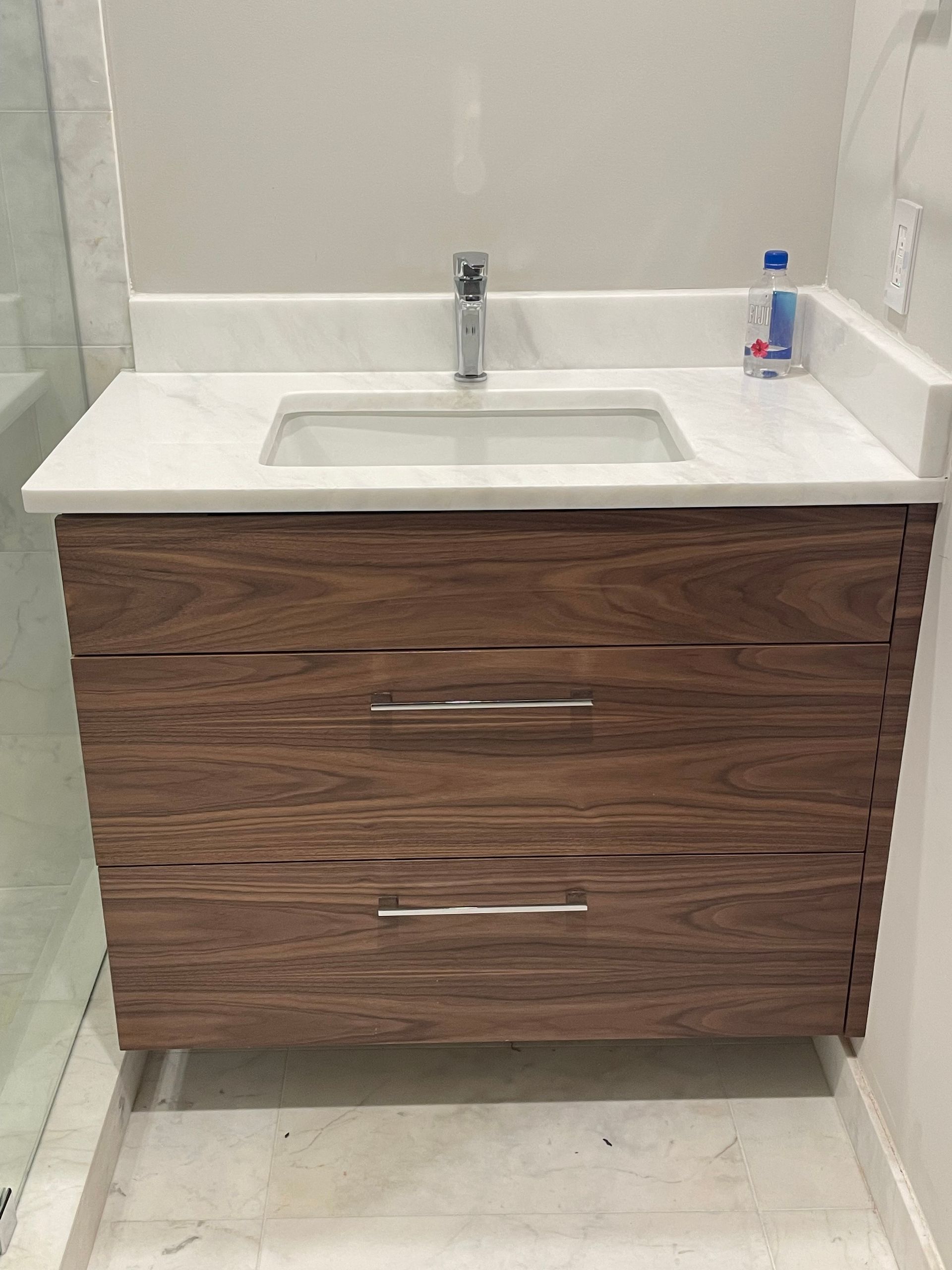 A bathroom sink with a wooden cabinet and a white counter top.