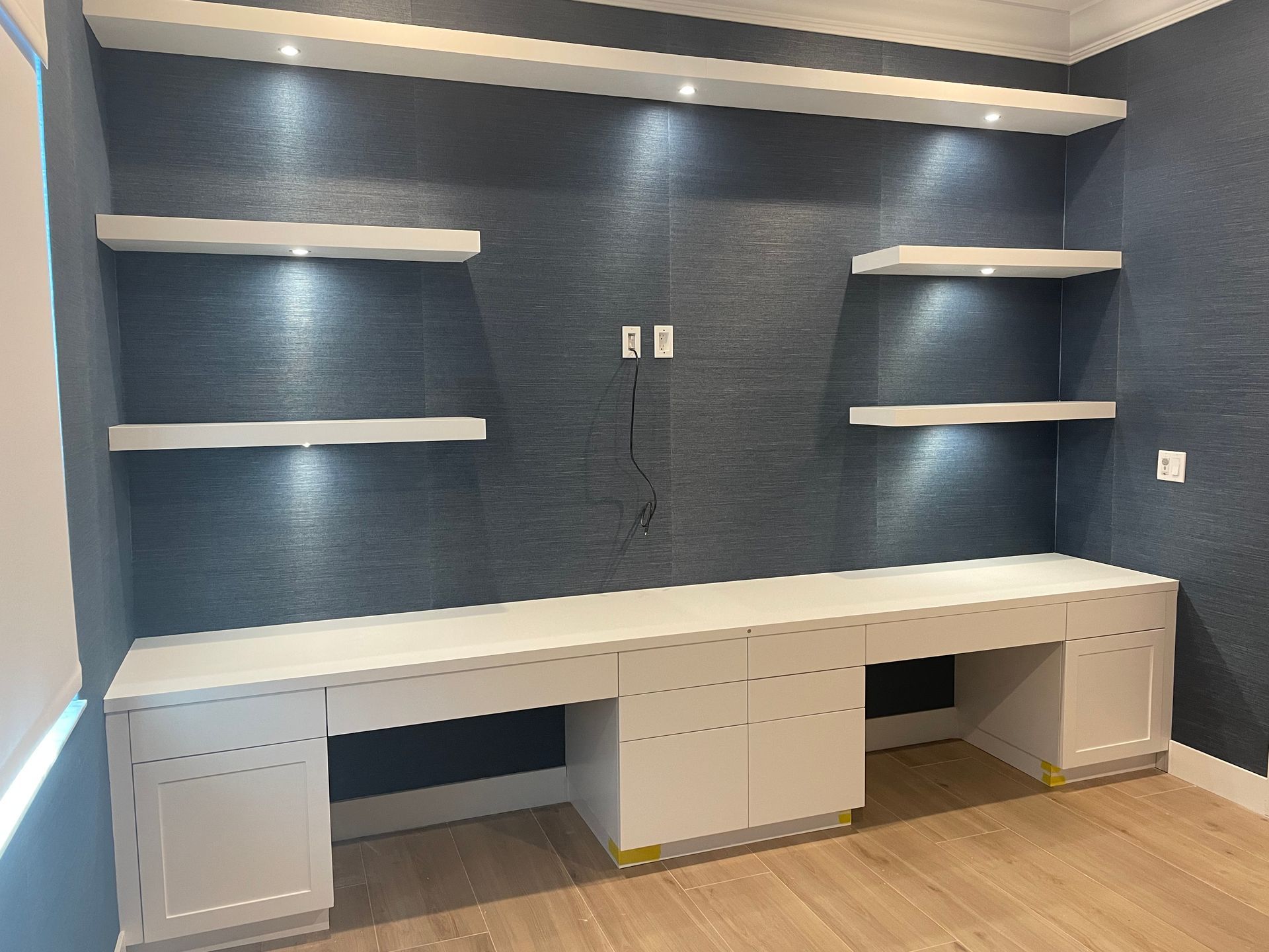 A room with a desk and shelves on the wall.