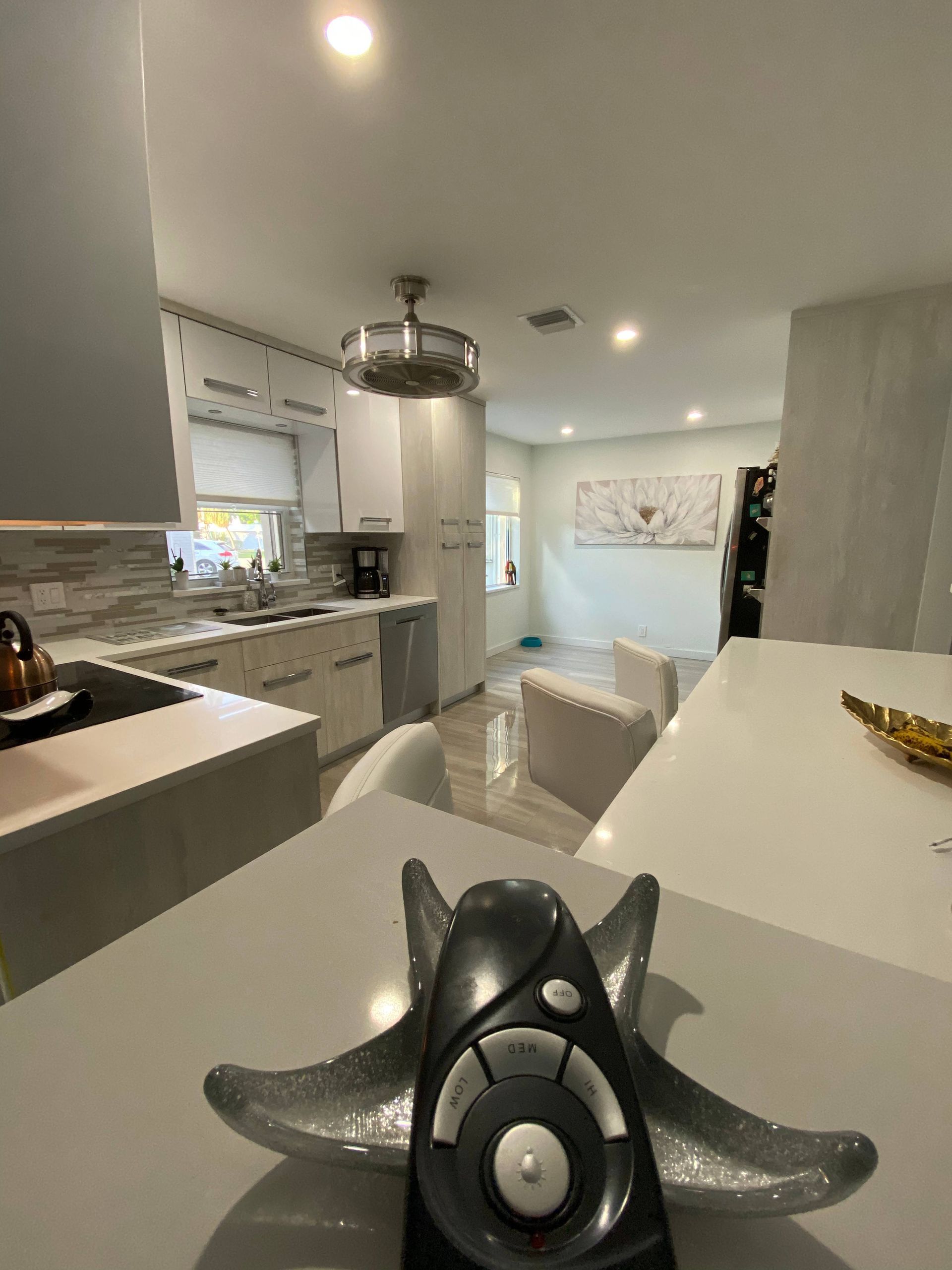 A remote control is sitting on a counter in a kitchen.