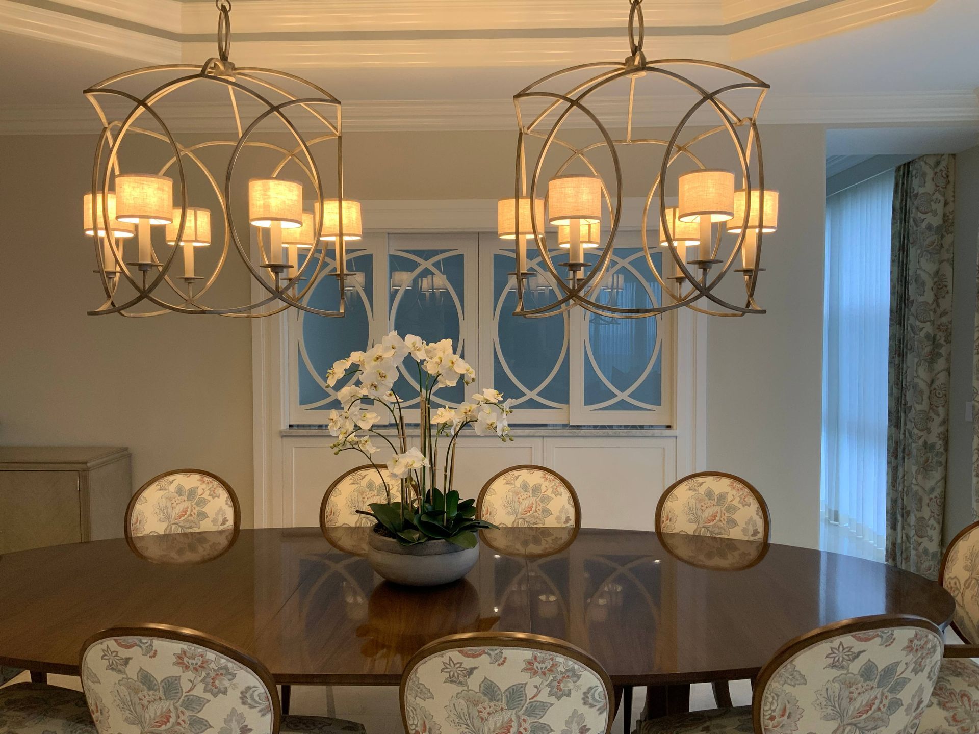 A dining room with a table and chairs and a chandelier hanging from the ceiling.