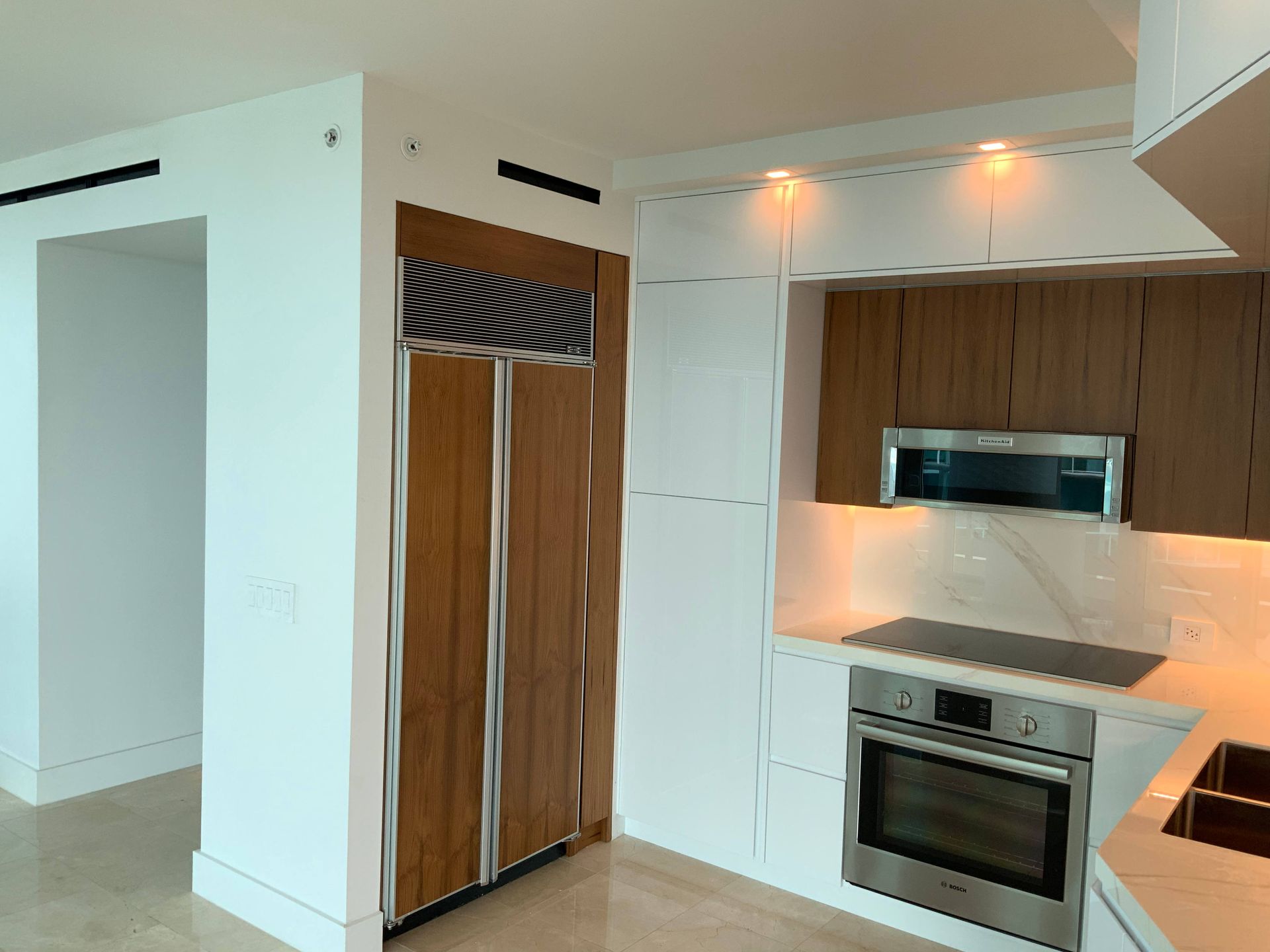 An empty kitchen with white cabinets and stainless steel appliances