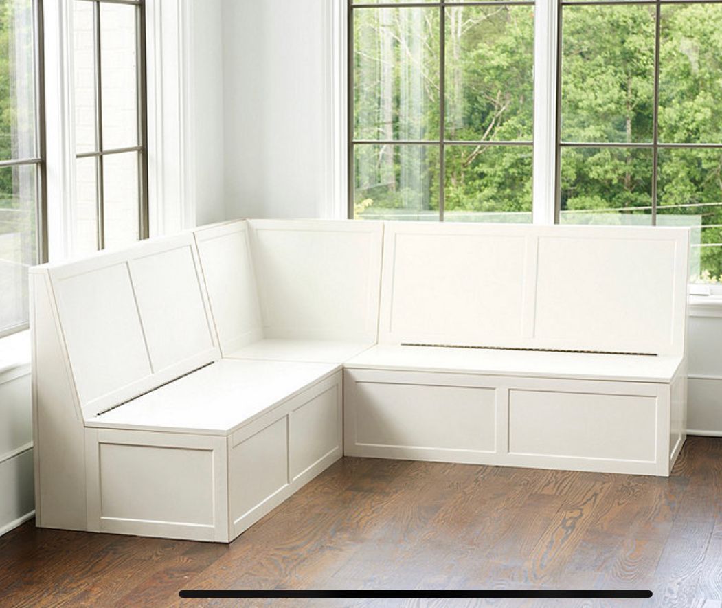 A white bench is sitting in front of a window in a living room.