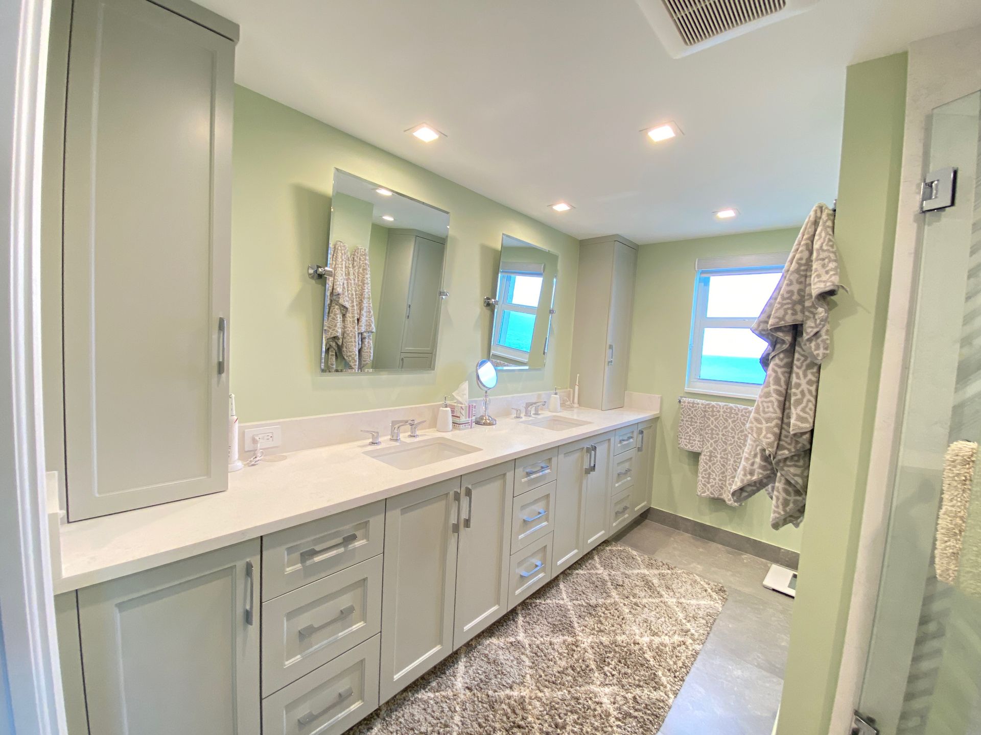 A bathroom with two sinks , two mirrors , and a rug.