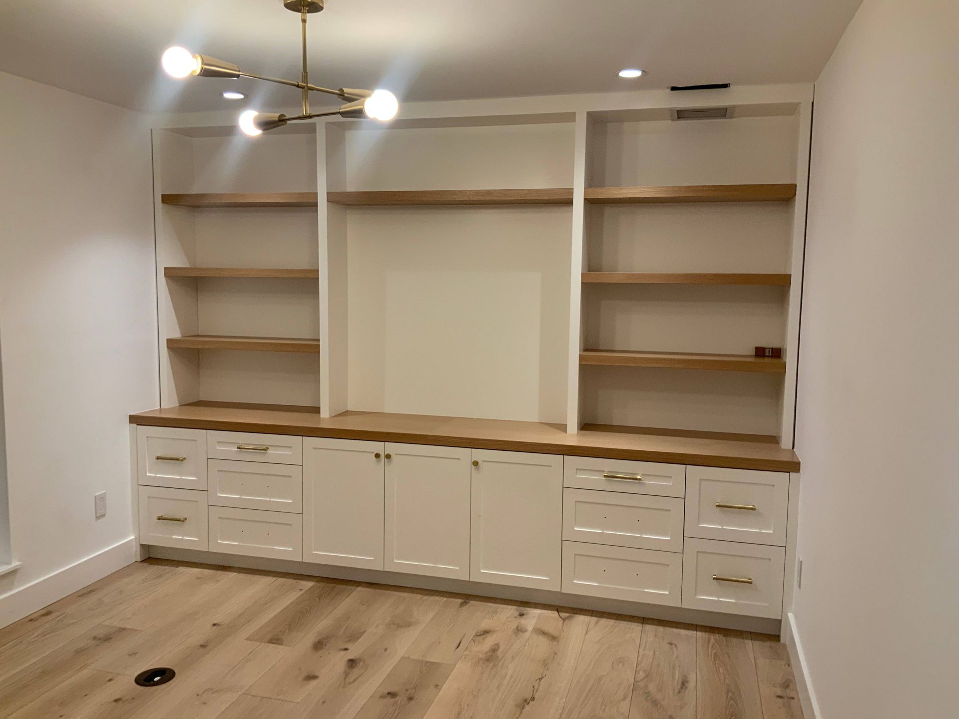 A room with white cabinets and wooden shelves.
