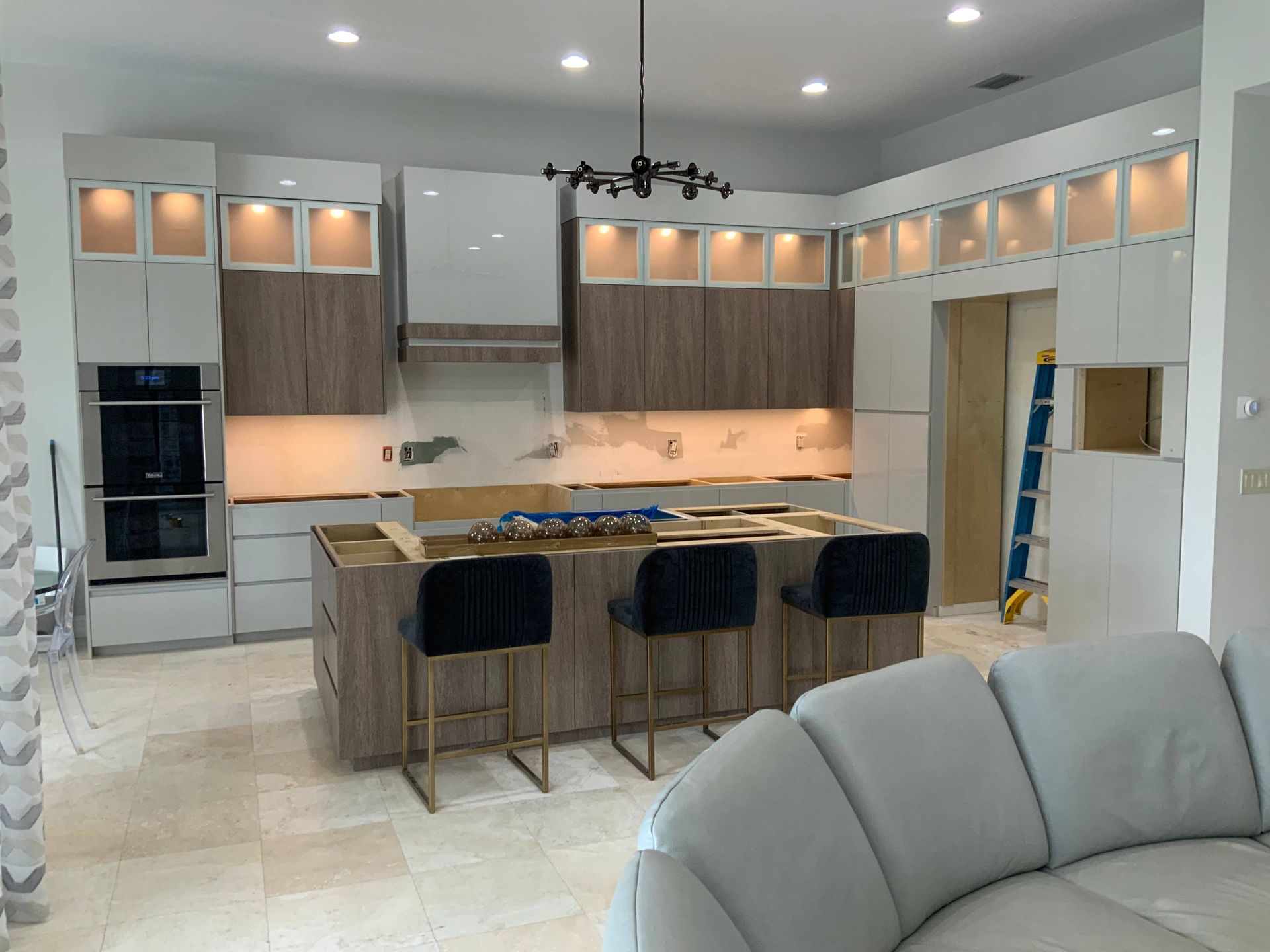 A kitchen with a large island and stools in a living room.