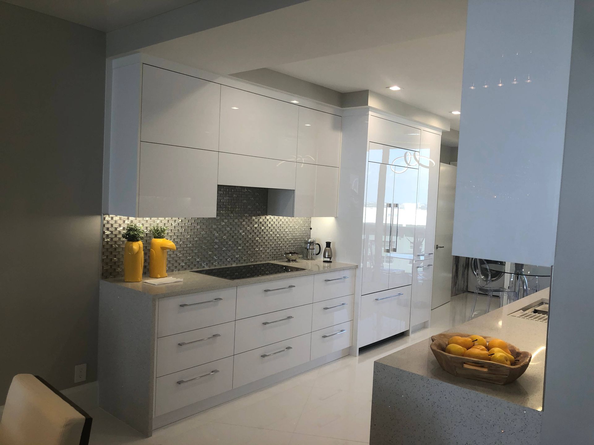 A kitchen with white cabinets and a bowl of lemons on the counter