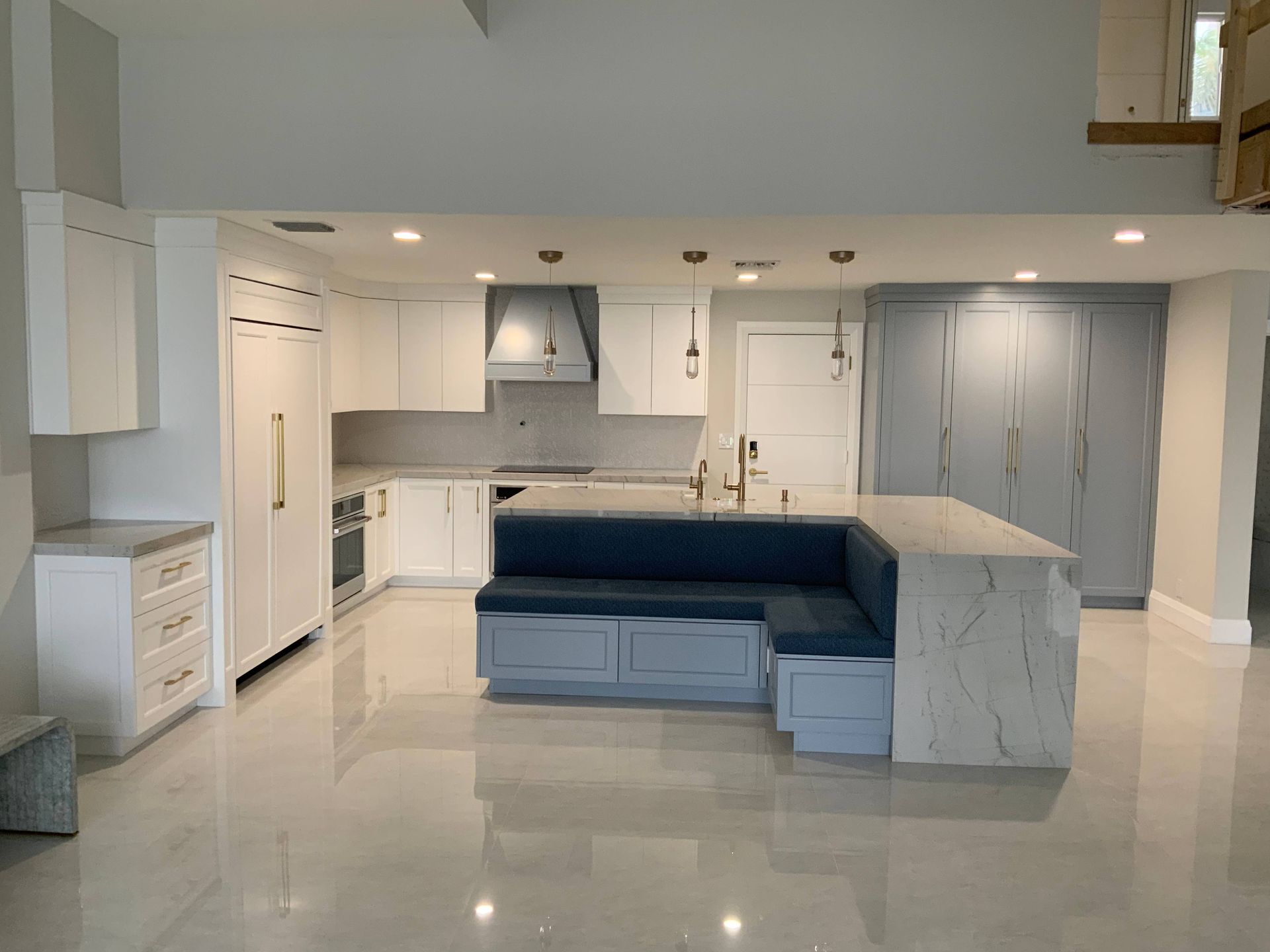 A kitchen with white cabinets and a blue couch in the middle.