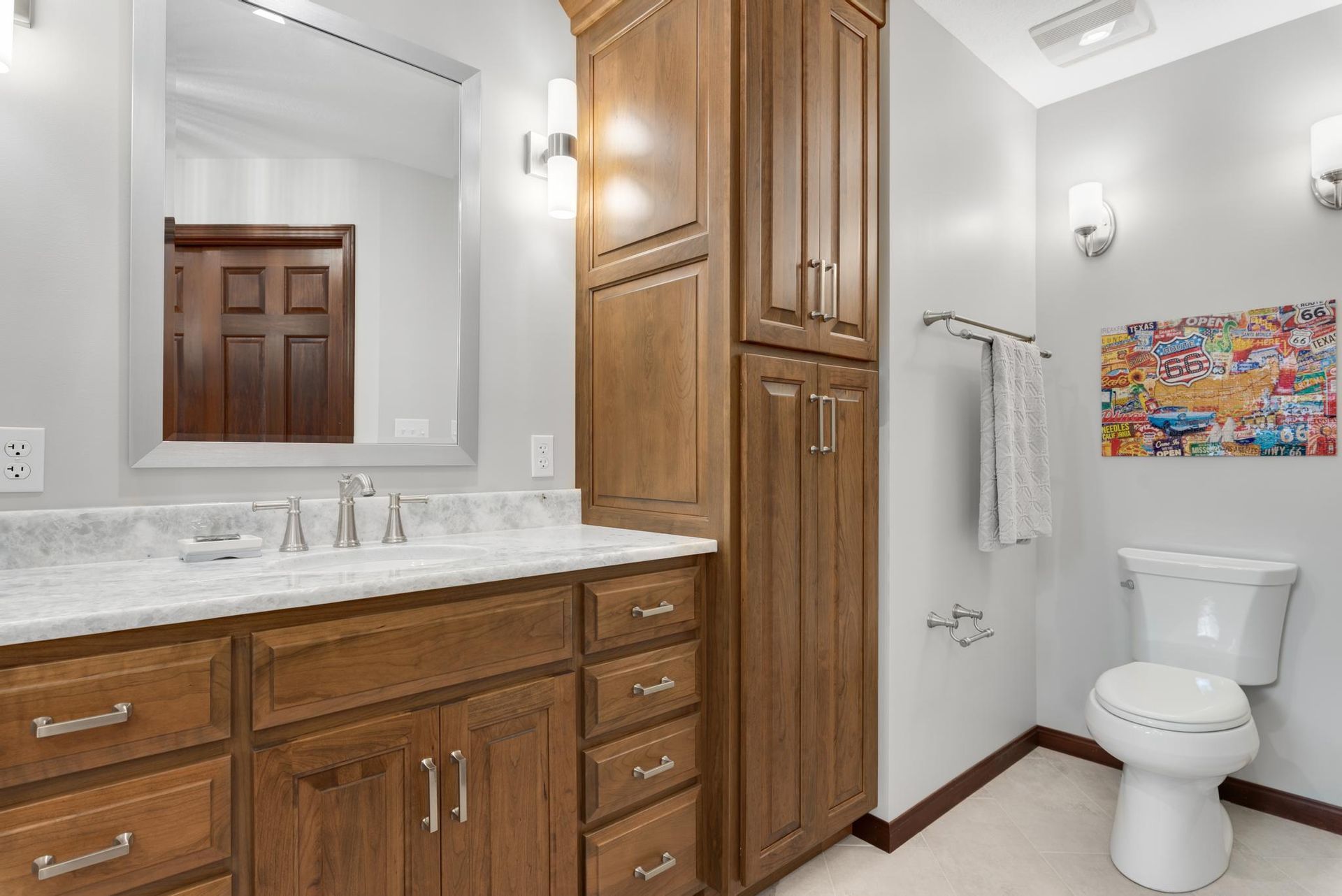 Bathroom with wooden cabinets, white countertop, and a toilet.