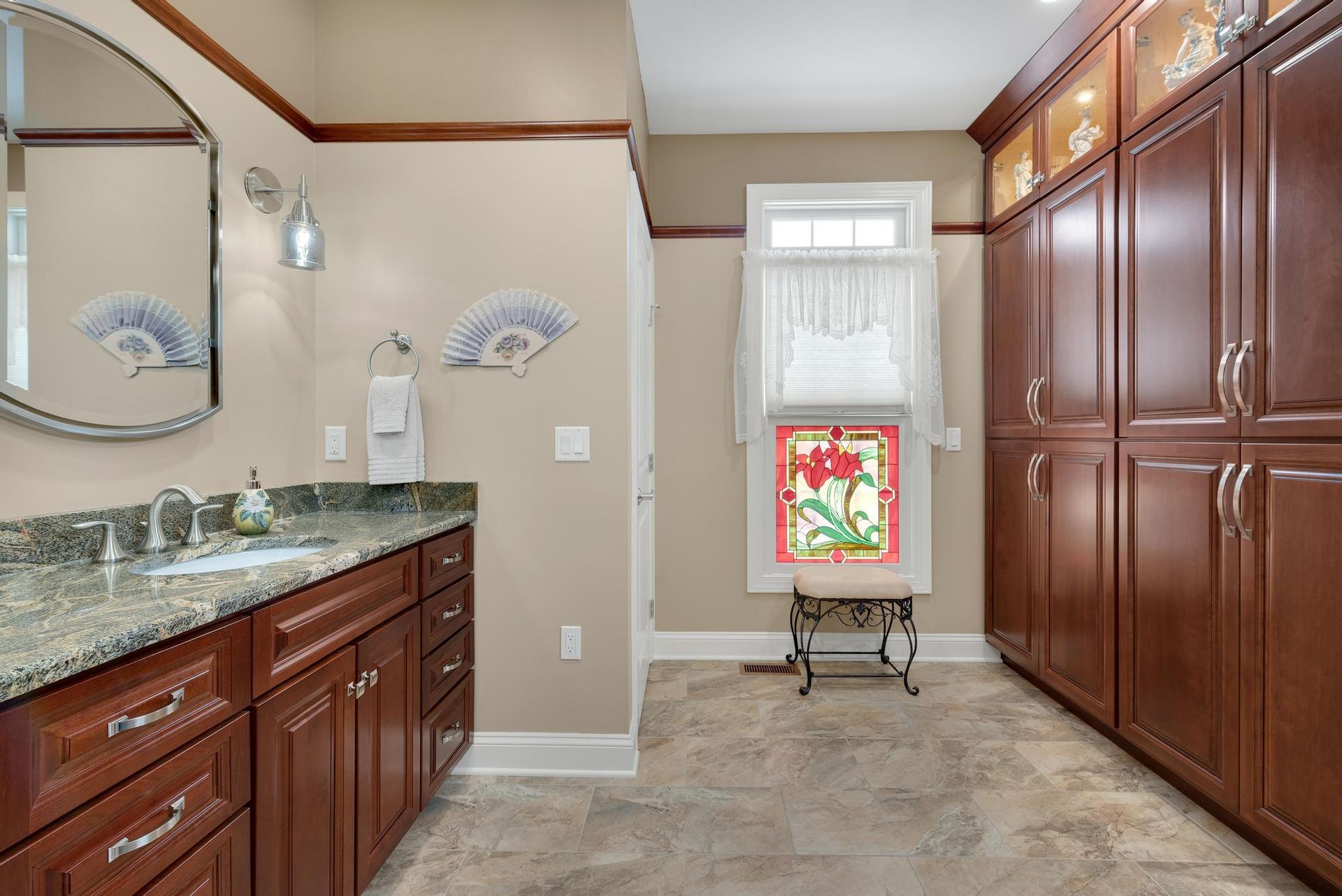 Bathroom with dark wood cabinets, a granite countertop, and a stained-glass window.