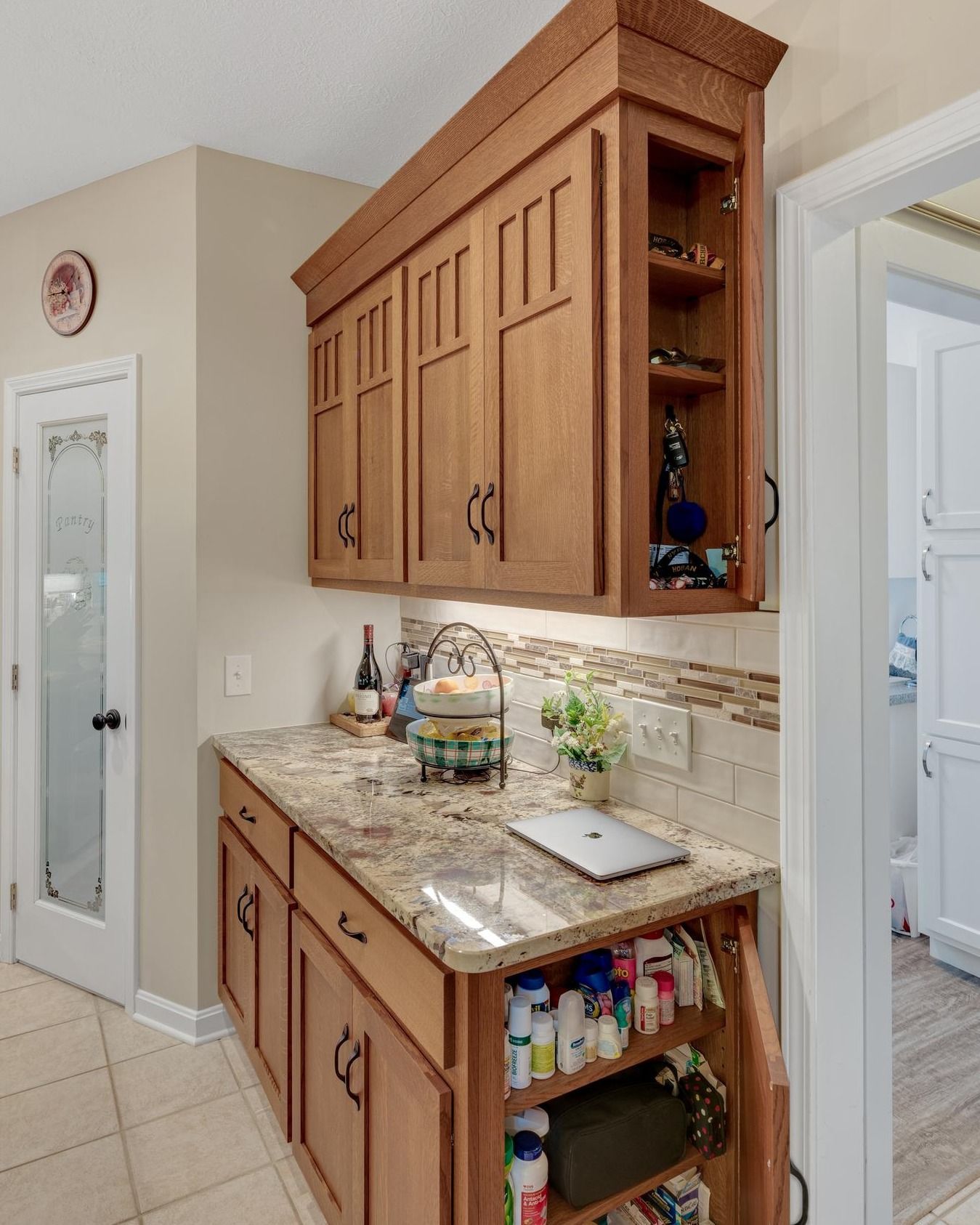 Kitchen with wood cabinets, granite countertop, and pull-out storage. A laptop sits on the counter.