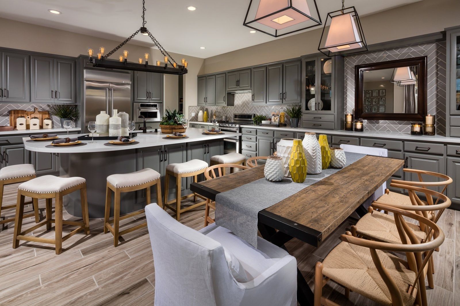 Modern gray kitchen with island, wood dining table, and bar seating under pendant lights.