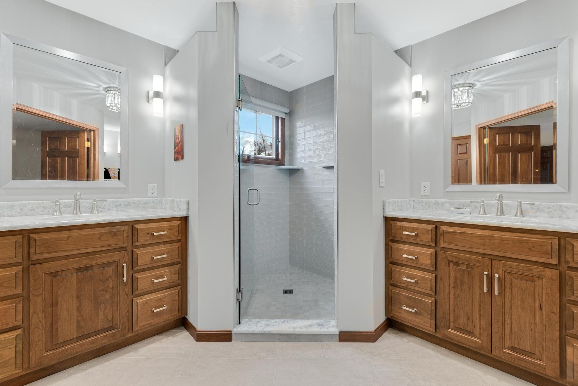 Bathroom with two sinks, a walk-in shower, and wooden cabinets.