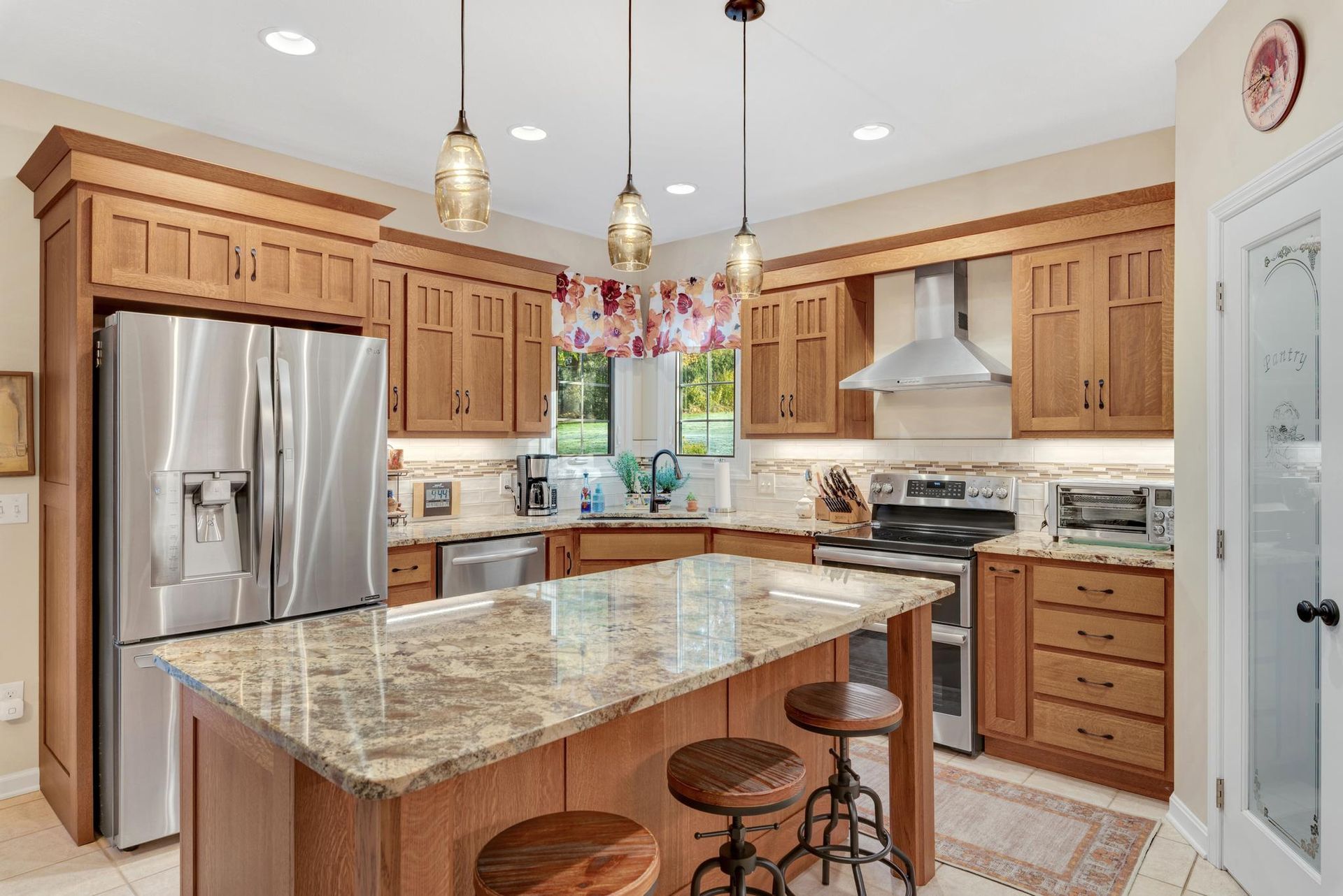 Kitchen with wooden cabinets, stainless steel appliances, granite island, and pendant lights.