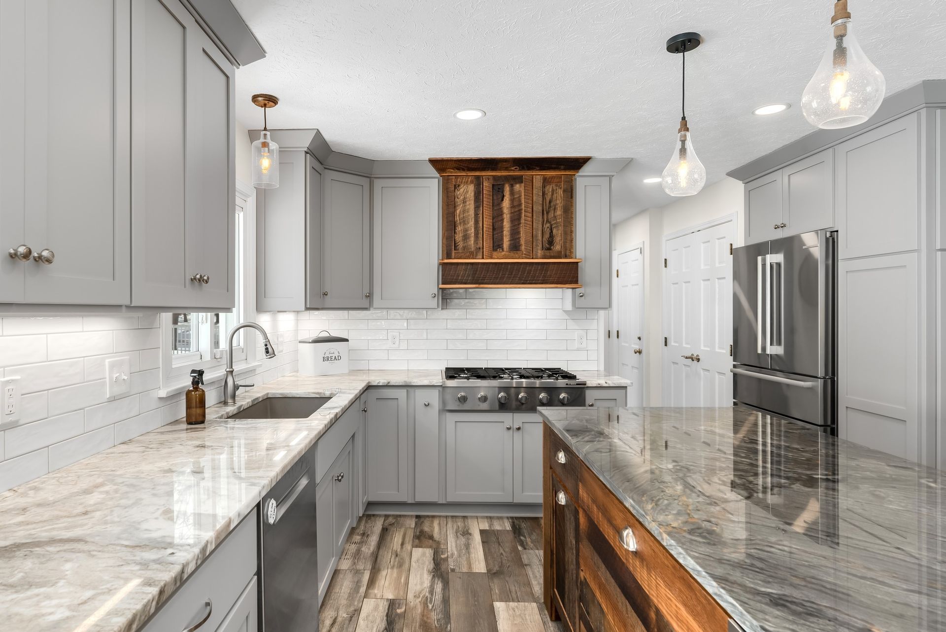 Gray and white kitchen with wood accents, stainless steel appliances, and a marble countertop.