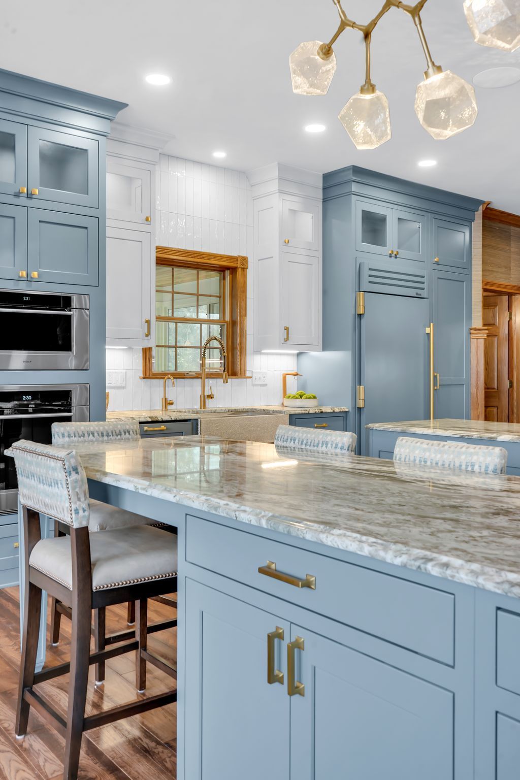 Blue and white kitchen with island, granite countertops, and gold accents.