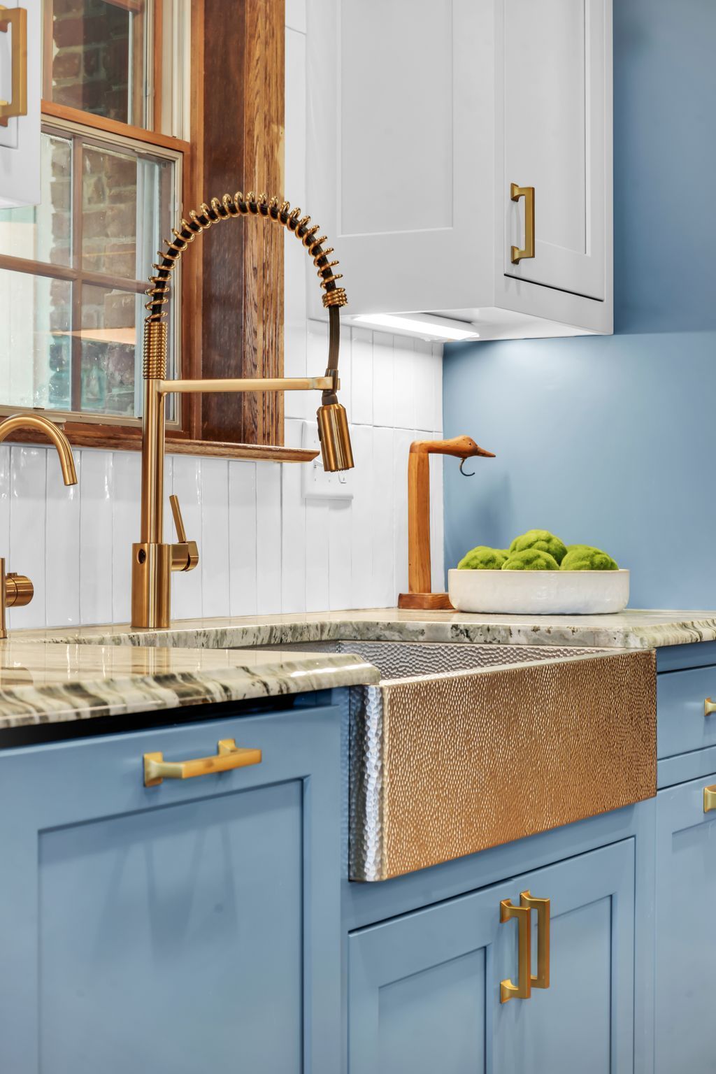 Blue and white kitchen with gold faucet, sink, and hardware.