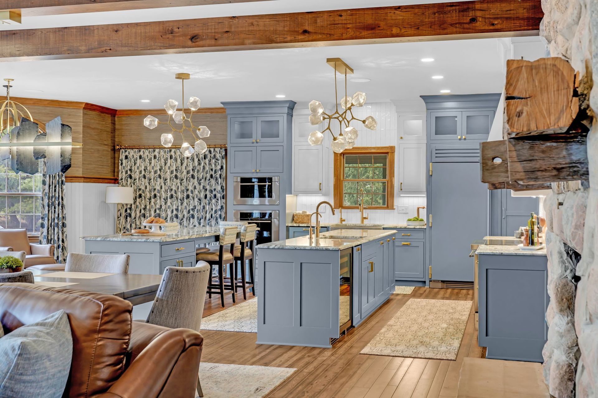 Blue kitchen with two islands, gold light fixtures, and wood accents.