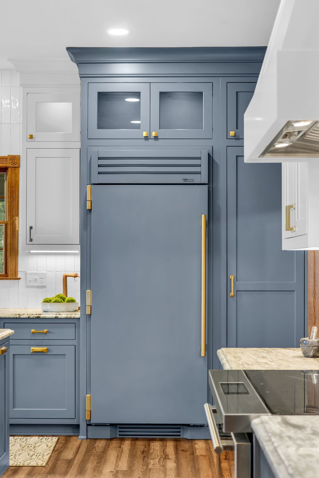 Blue kitchen refrigerator and cabinetry with brass hardware.