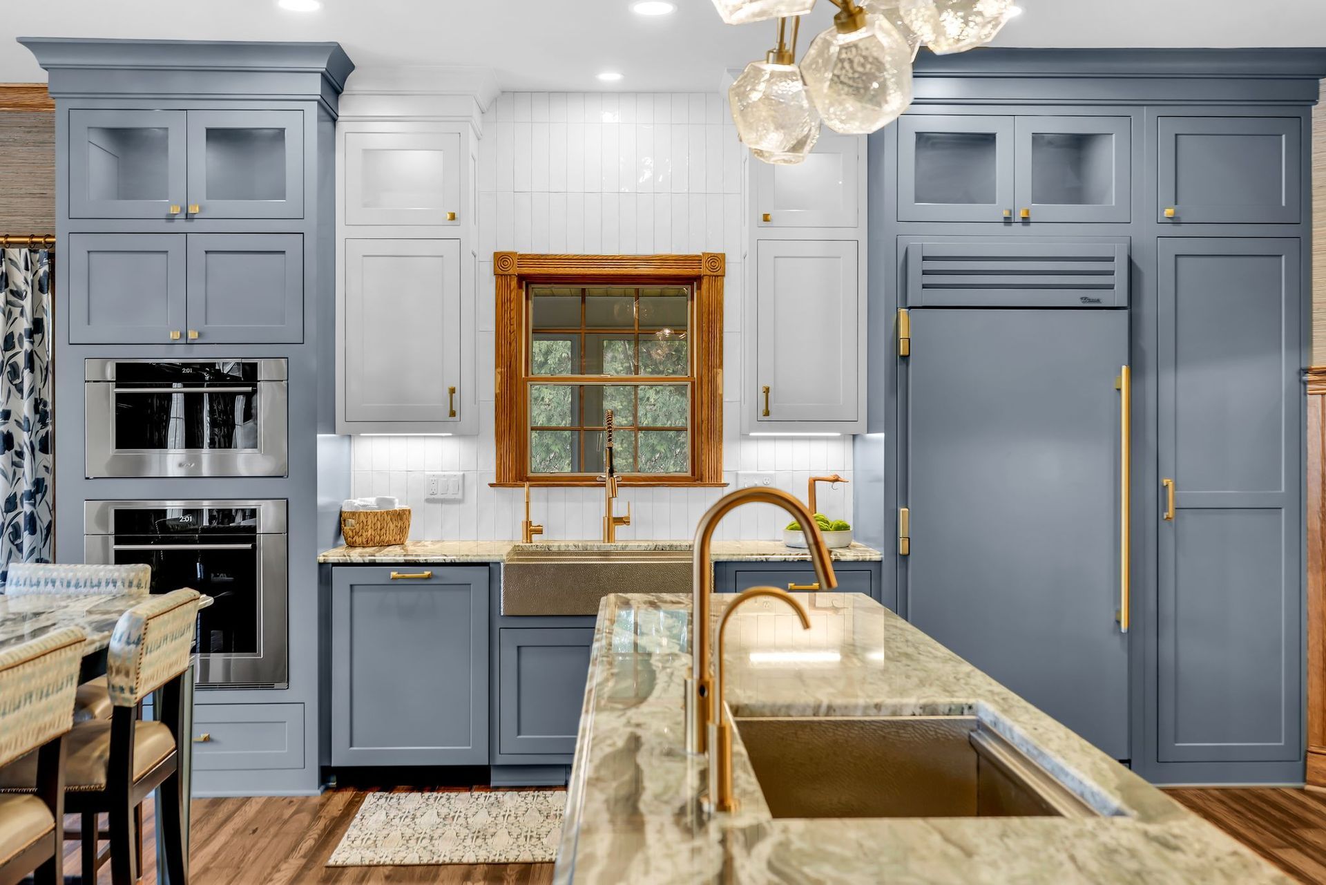 Blue and white kitchen with granite countertops, gold fixtures, and a large refrigerator.