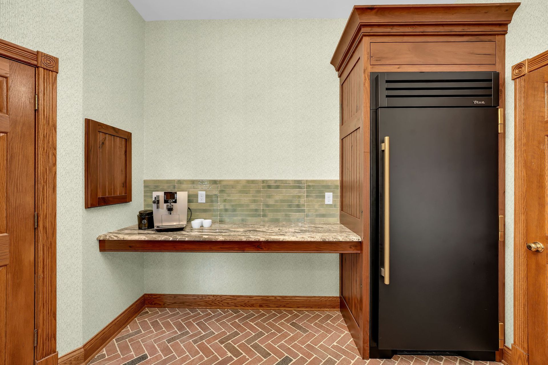 Small kitchen area with a dark refrigerator, coffee maker, and wooden cabinetry.