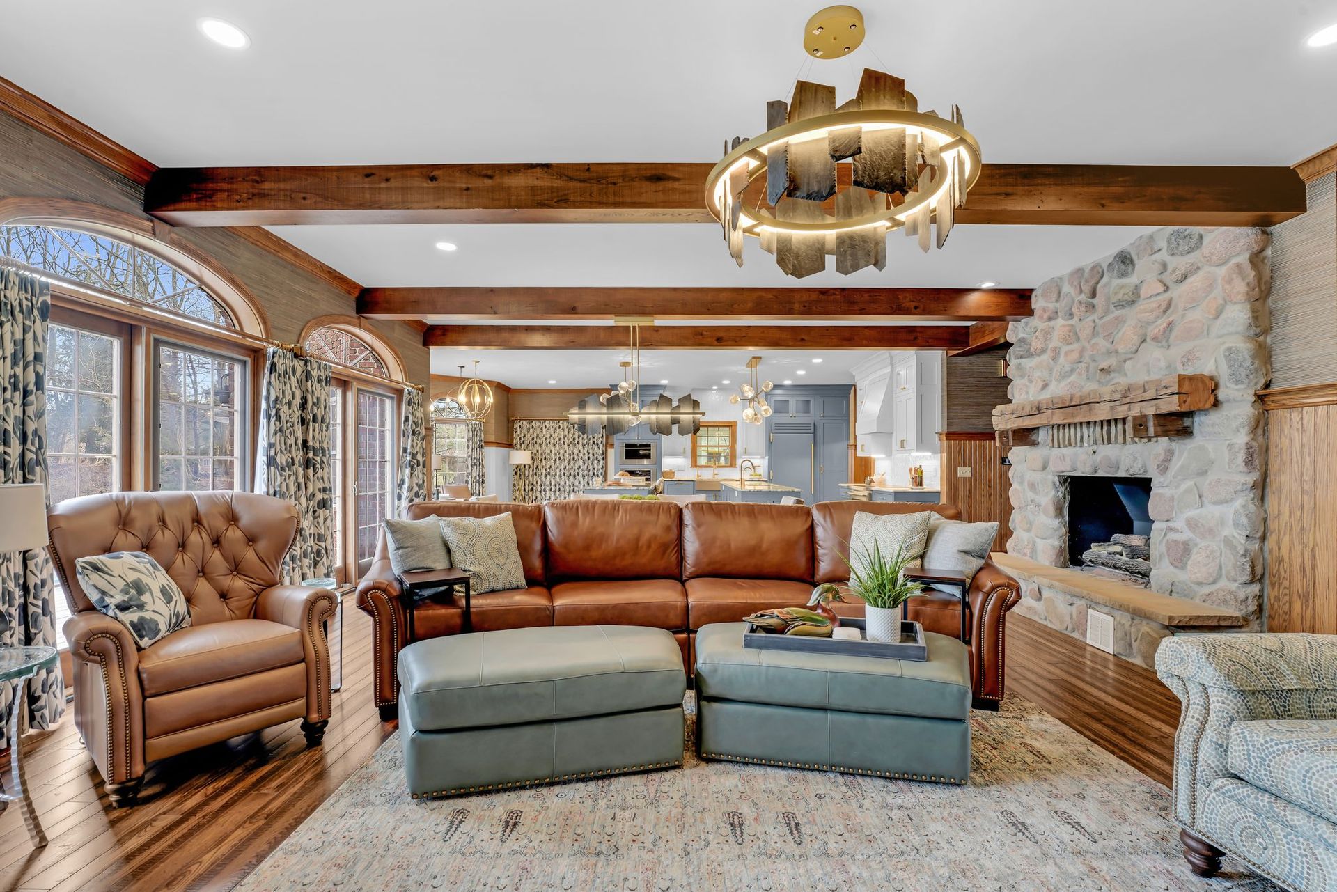 Living room with leather sofa, stone fireplace, and open kitchen view.