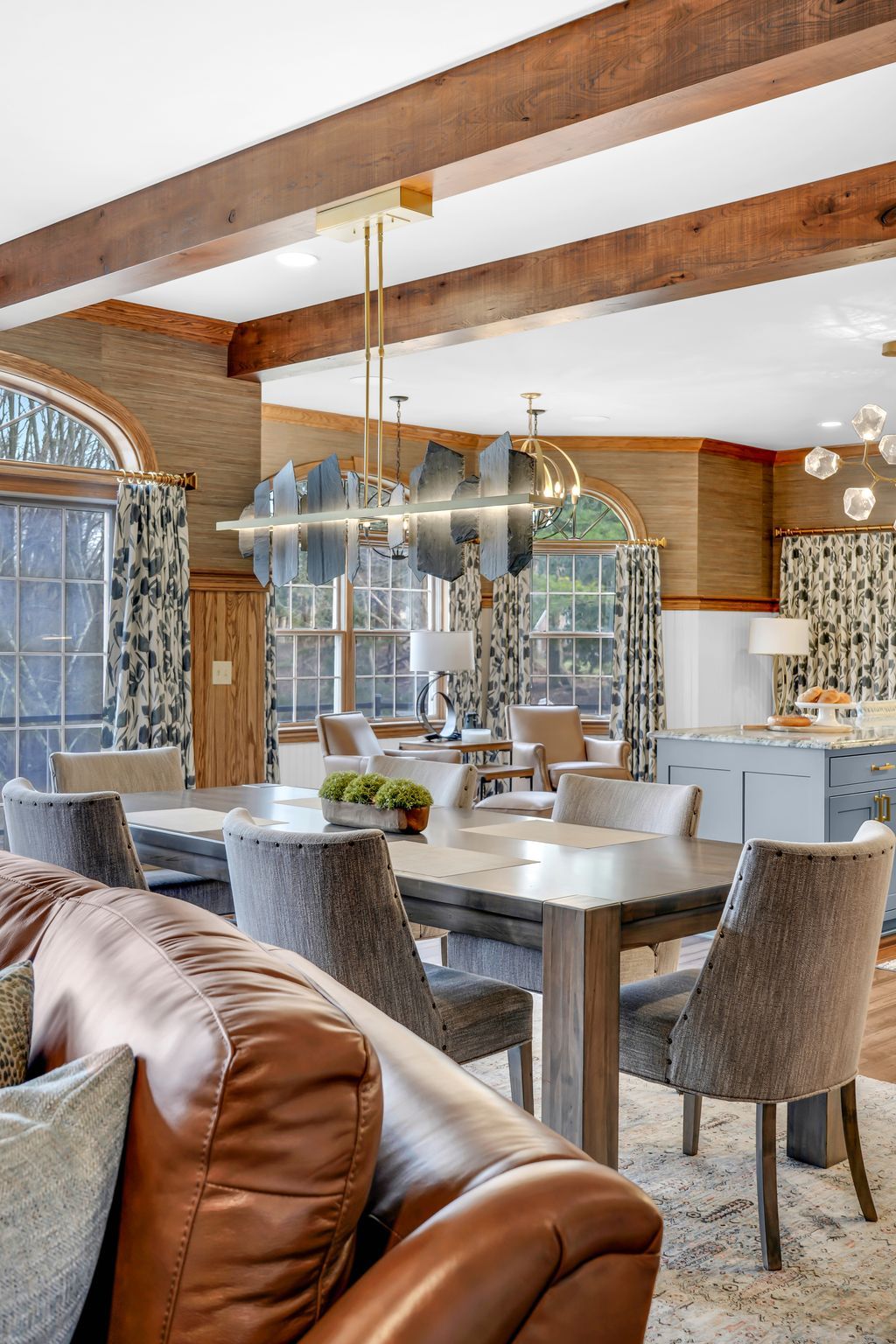 Dining room with a long wooden table, gray chairs, and an ornate light fixture.