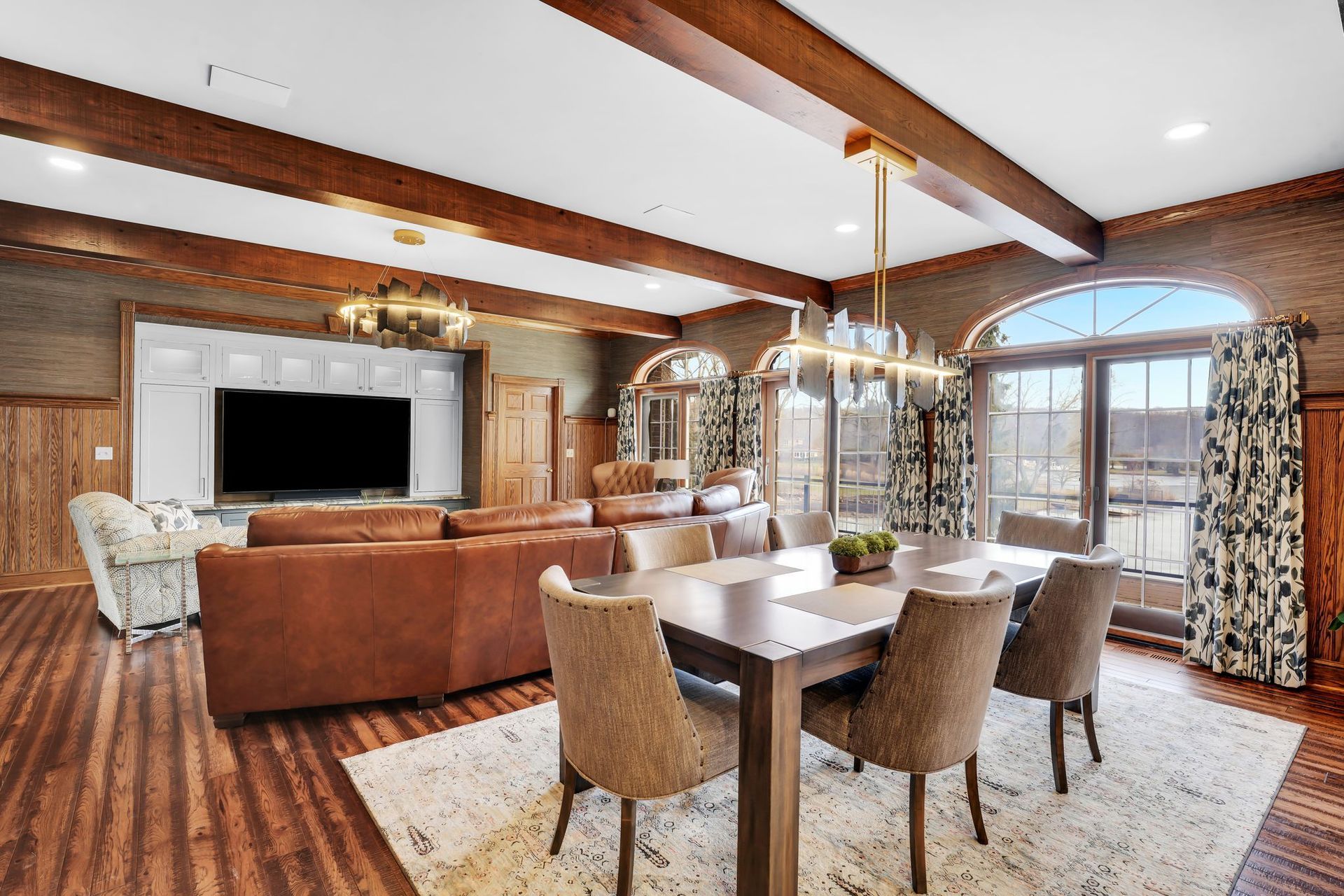 Spacious dining and living area with wood beams, leather sofa, and a table set for six.