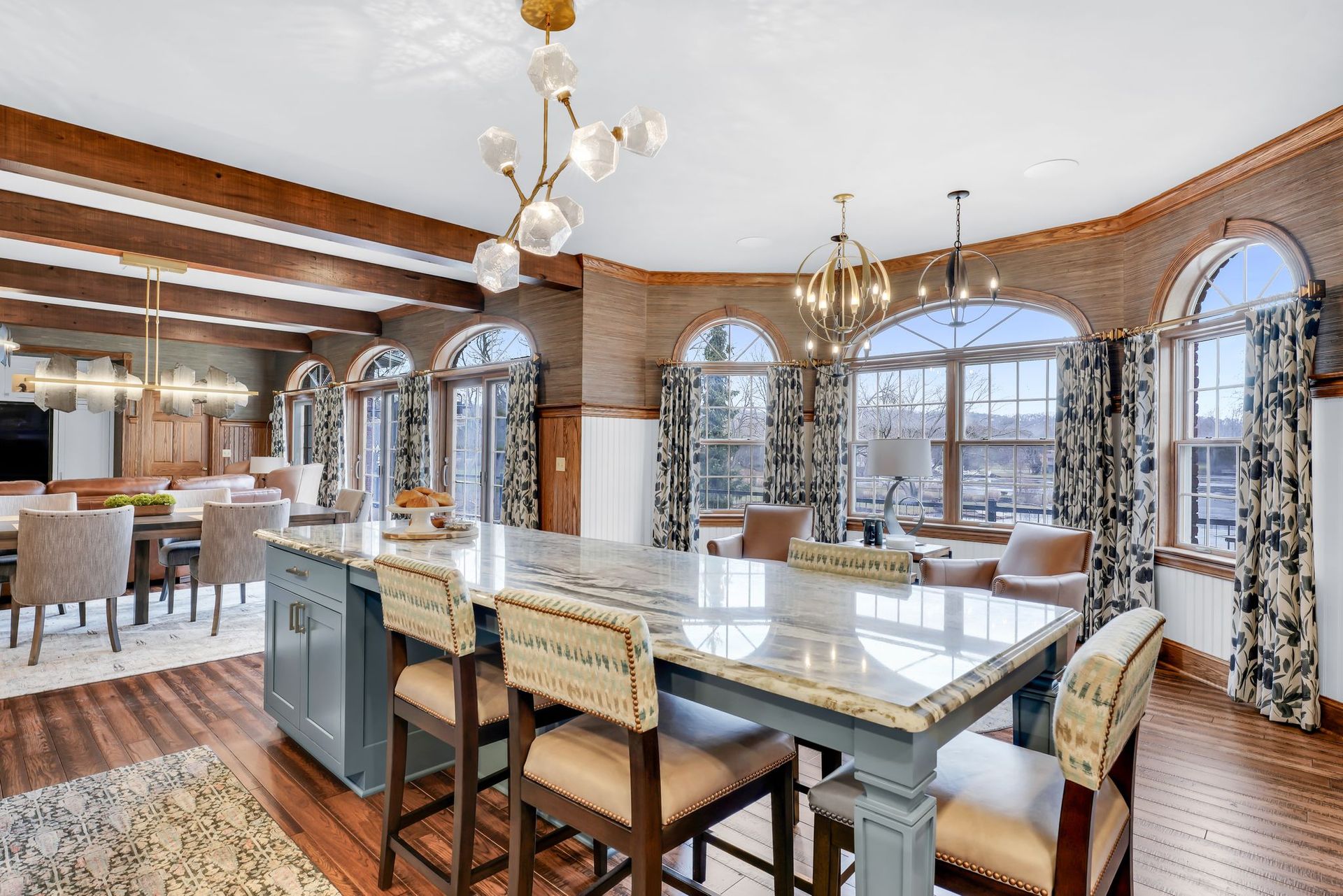 Spacious kitchen with island, seating, and large windows. Brown brick walls and light fixtures.