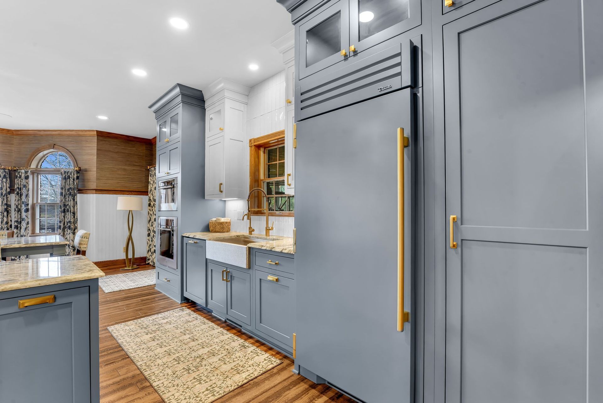 Blue and white kitchen with a built-in refrigerator, gold hardware, and a farmhouse sink.