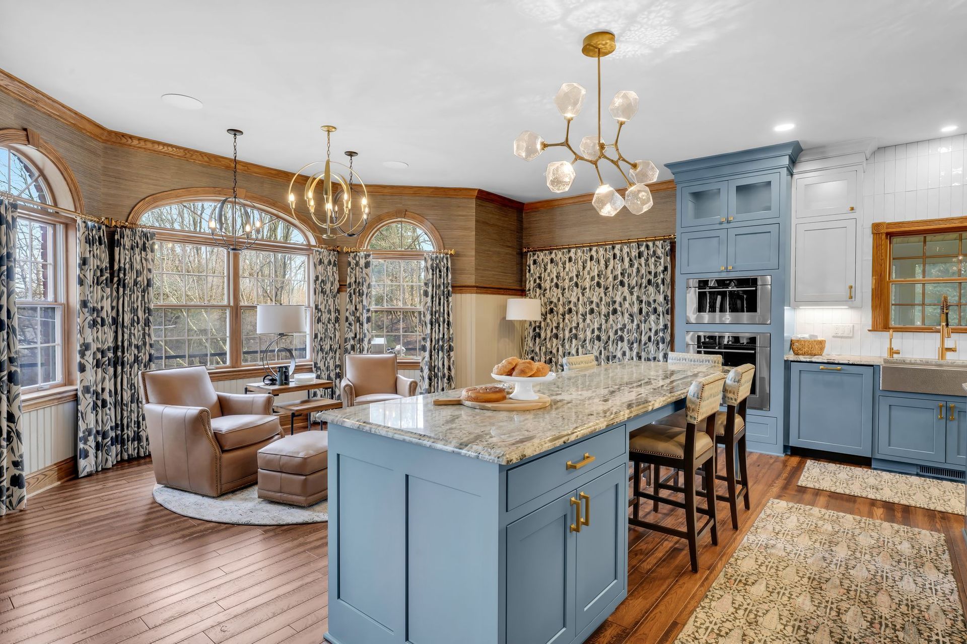 Spacious kitchen with blue island, granite countertop, and matching cabinets. Arched windows with floral drapes.