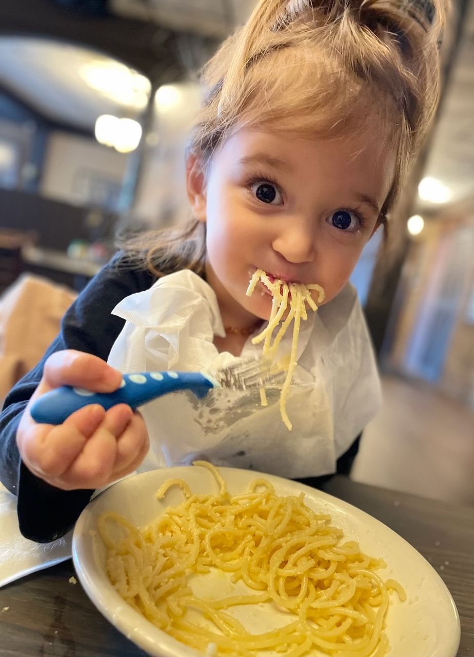 A little girl is eating spaghetti with a fork.