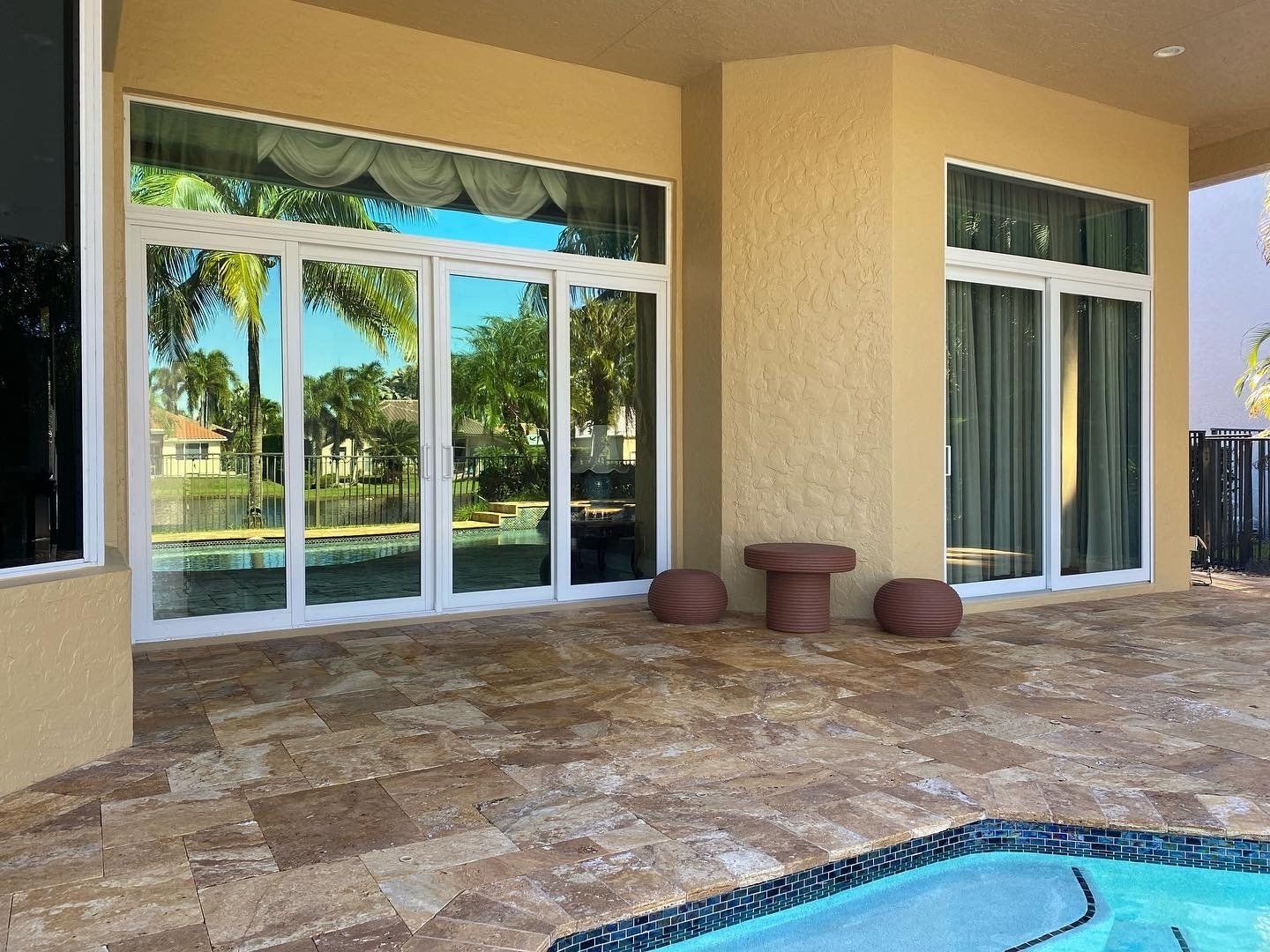 A patio with sliding glass doors and a pool in the background