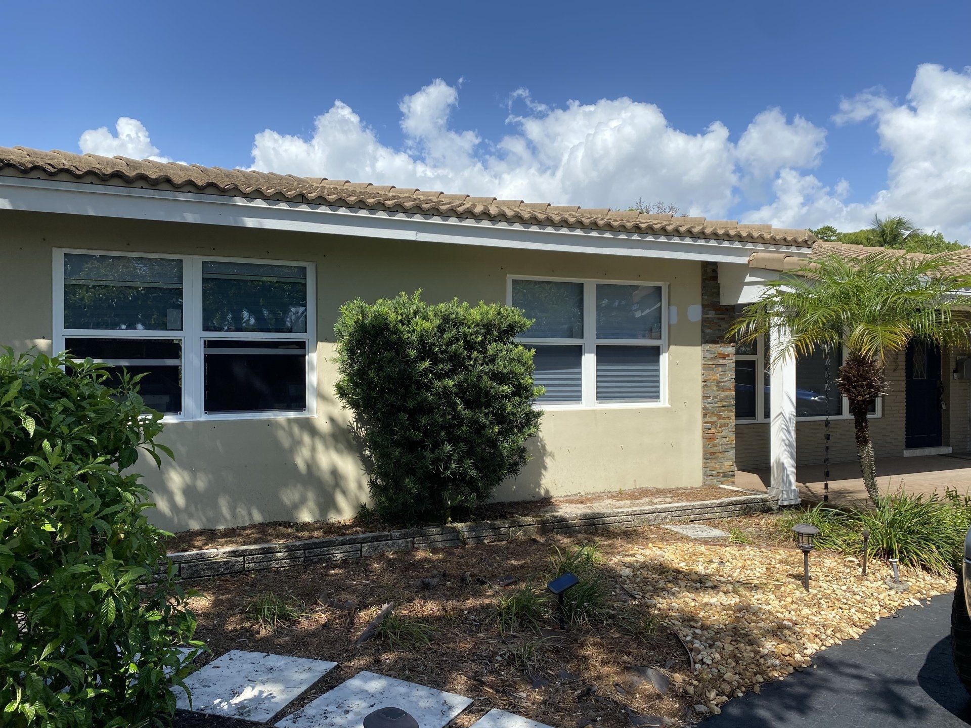 A house with a lot of windows and bushes in front of it.