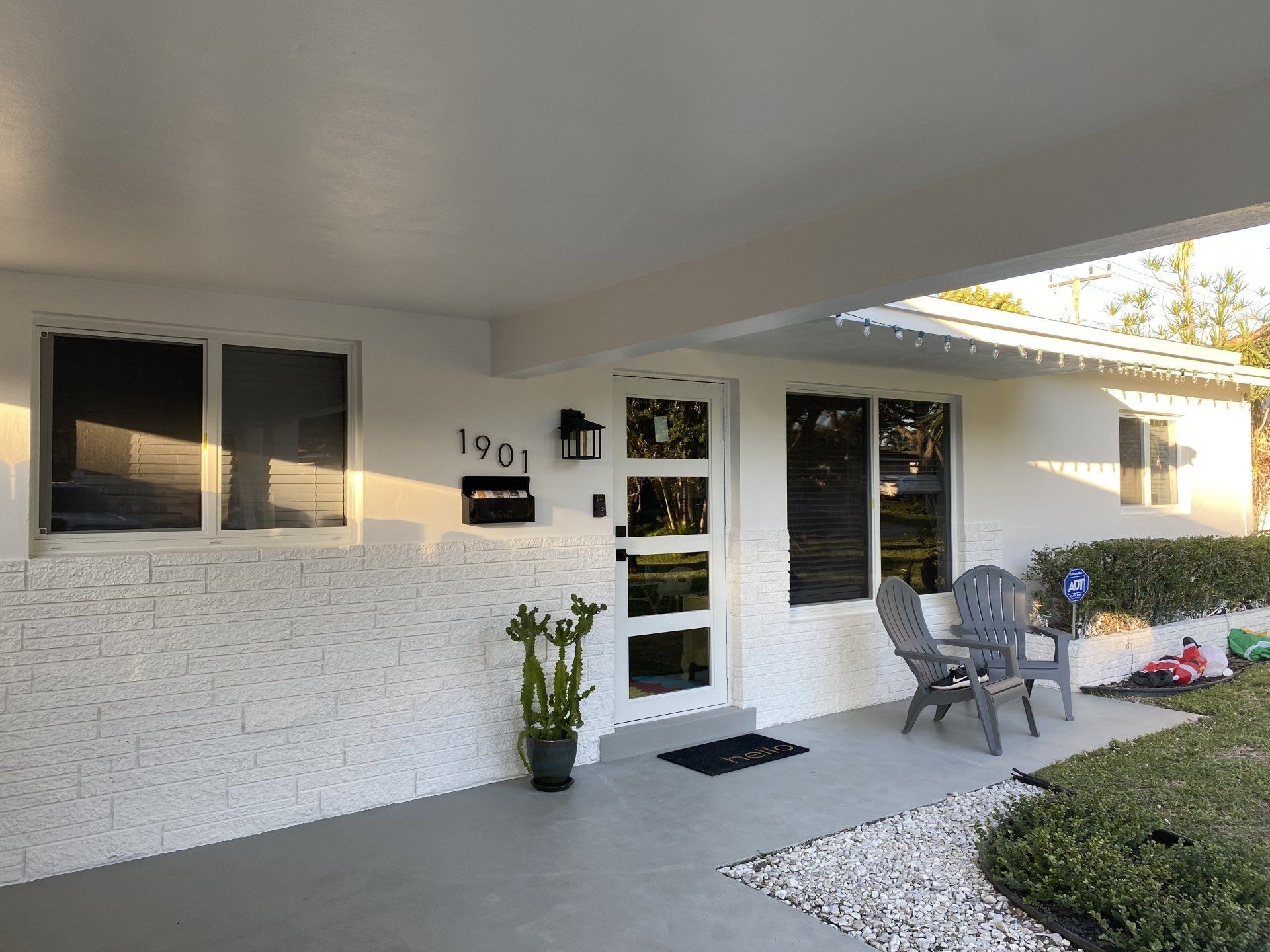 A white house with a porch and chairs in front of it.