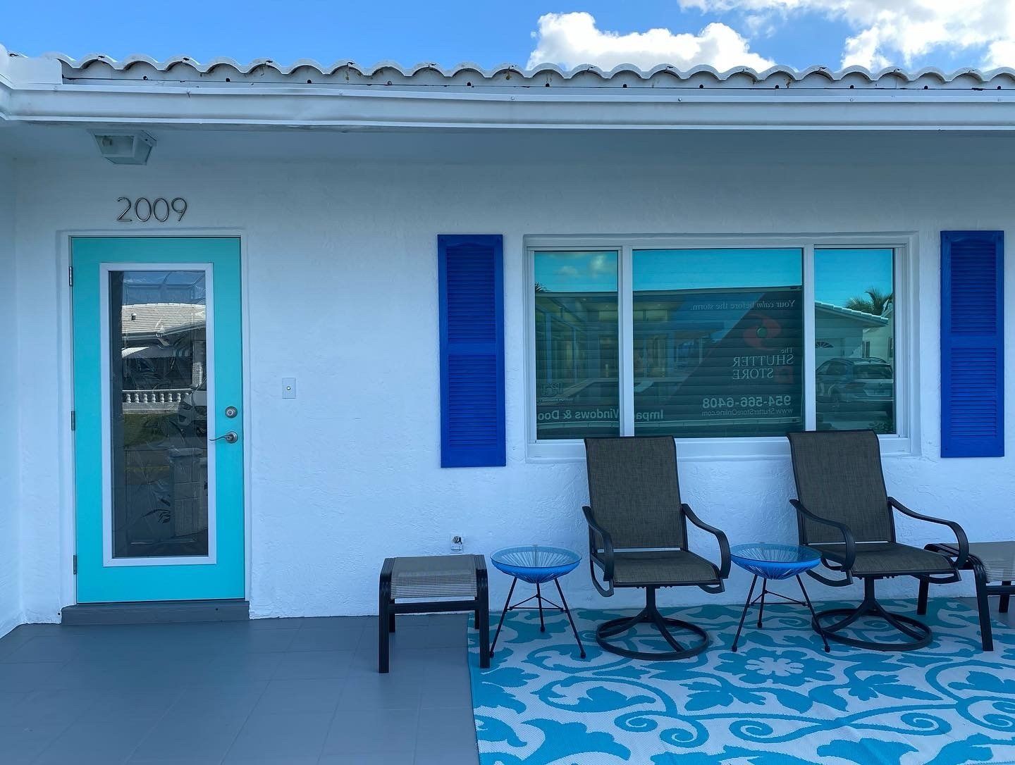 A white house with a blue door and blue shutters