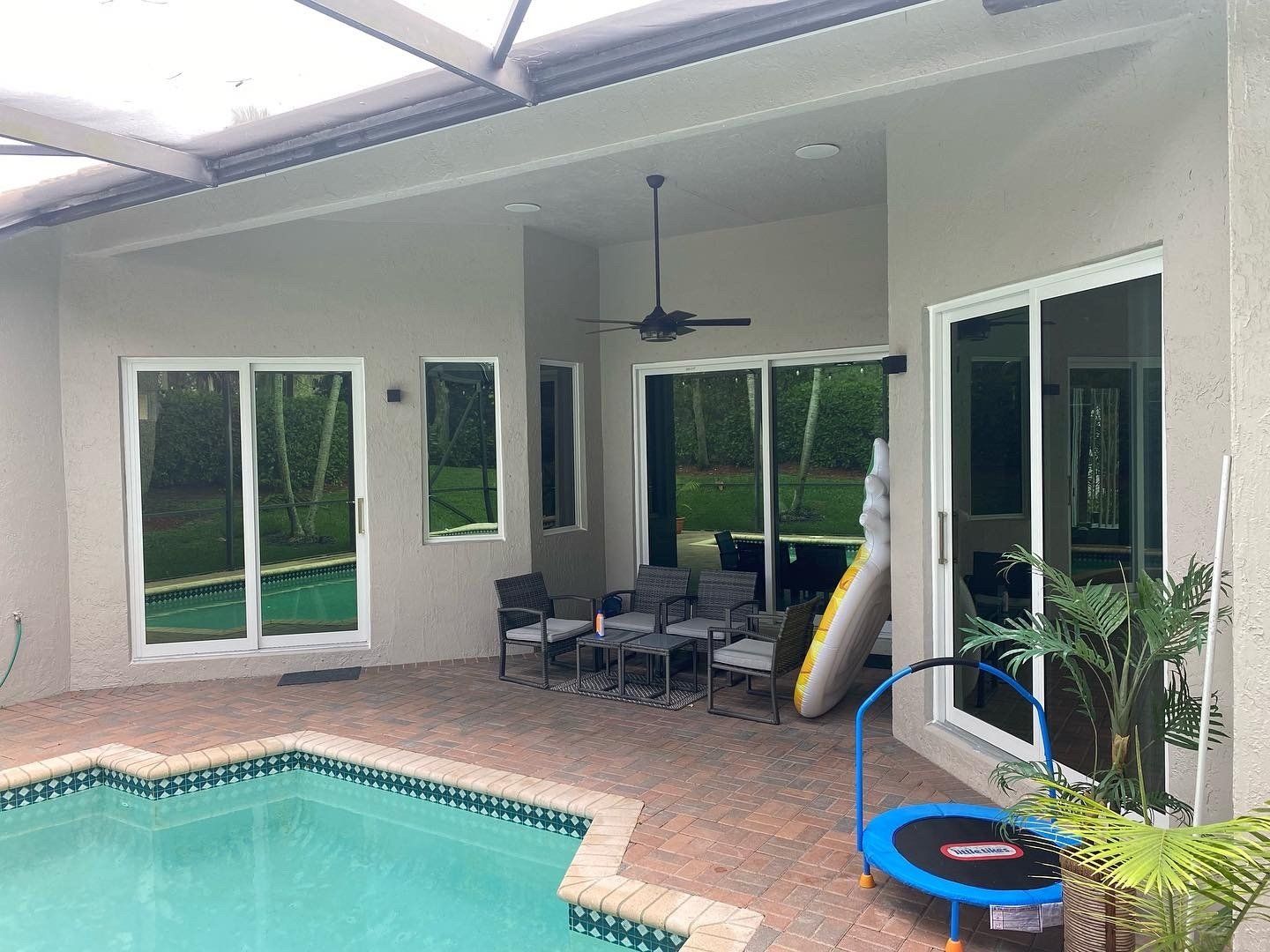 There is a trampoline in the backyard of a house next to a pool.