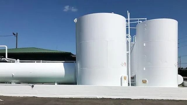 White industrial tanks against a blue sky, likely for storage at a facility.