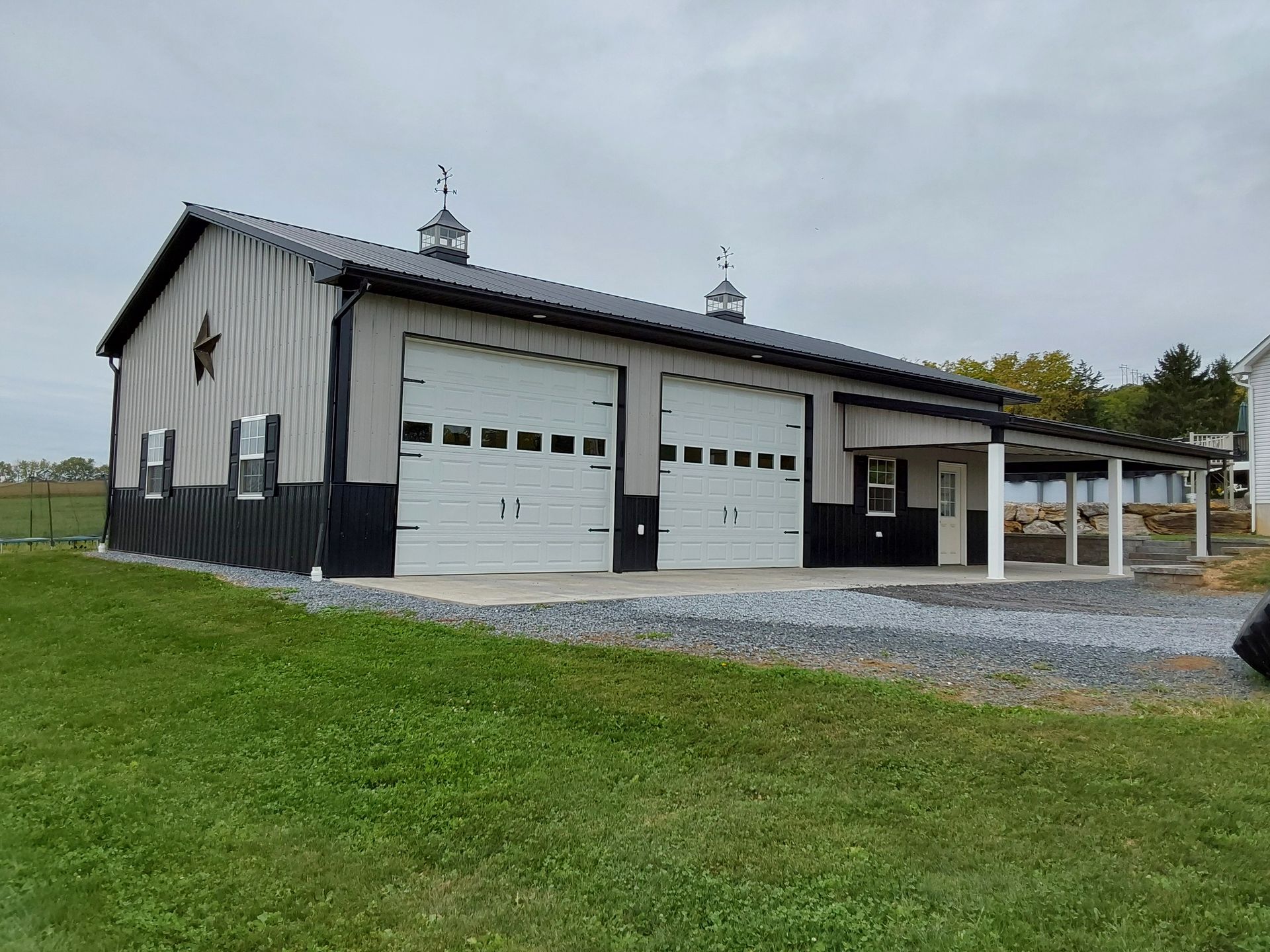 A large building with a lot of garage doors is sitting in the middle of a grassy field.