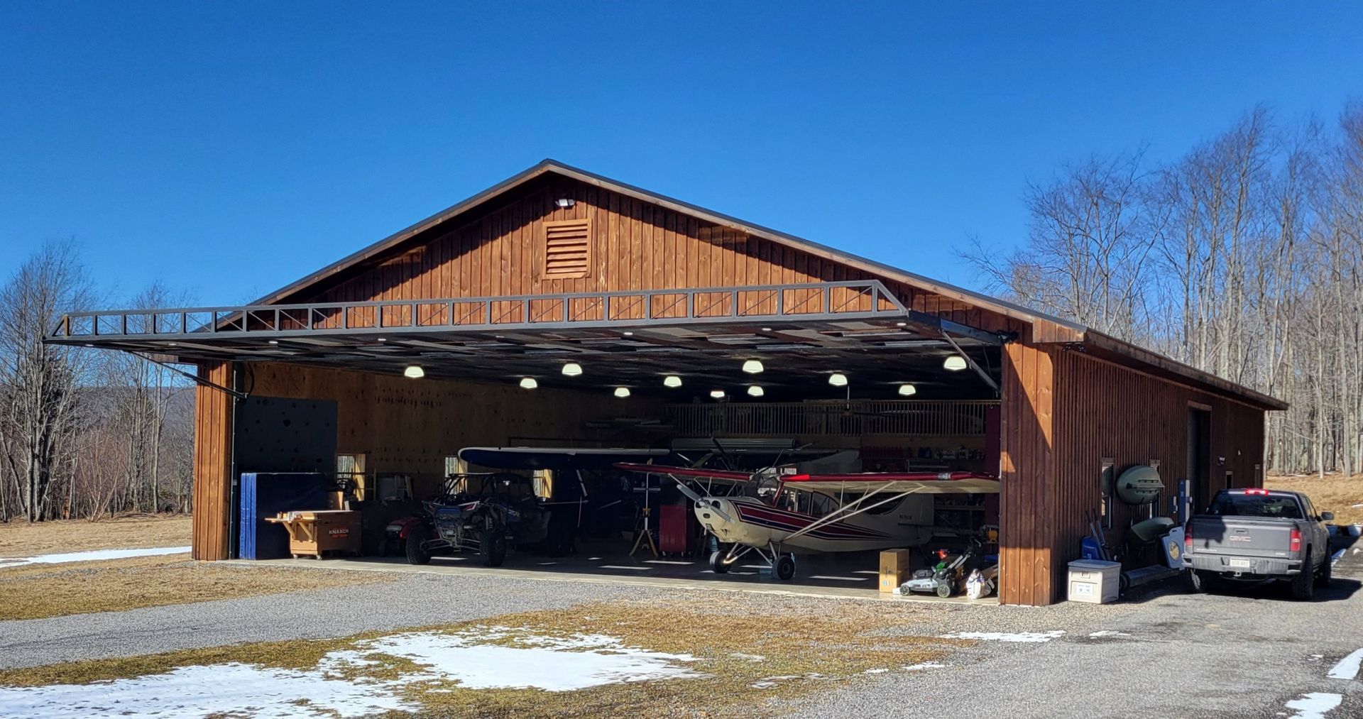 A plane is parked inside of a wooden hangar.