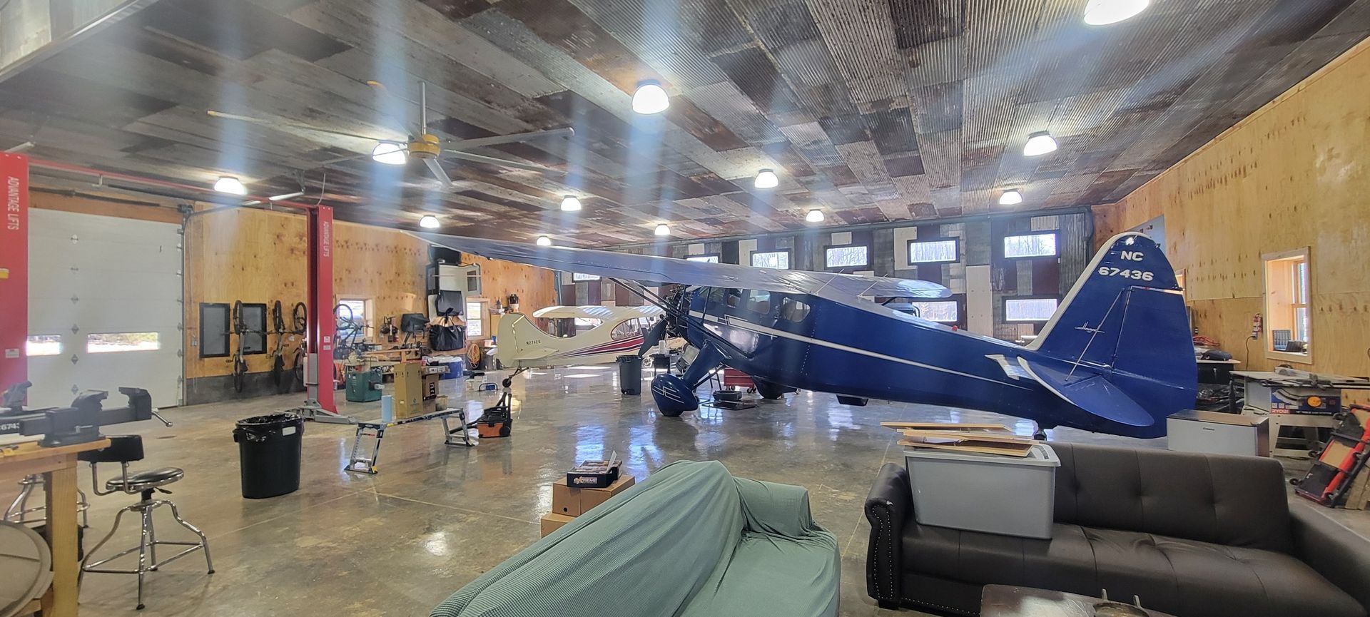 A large room with a blue airplane hanging from the ceiling.