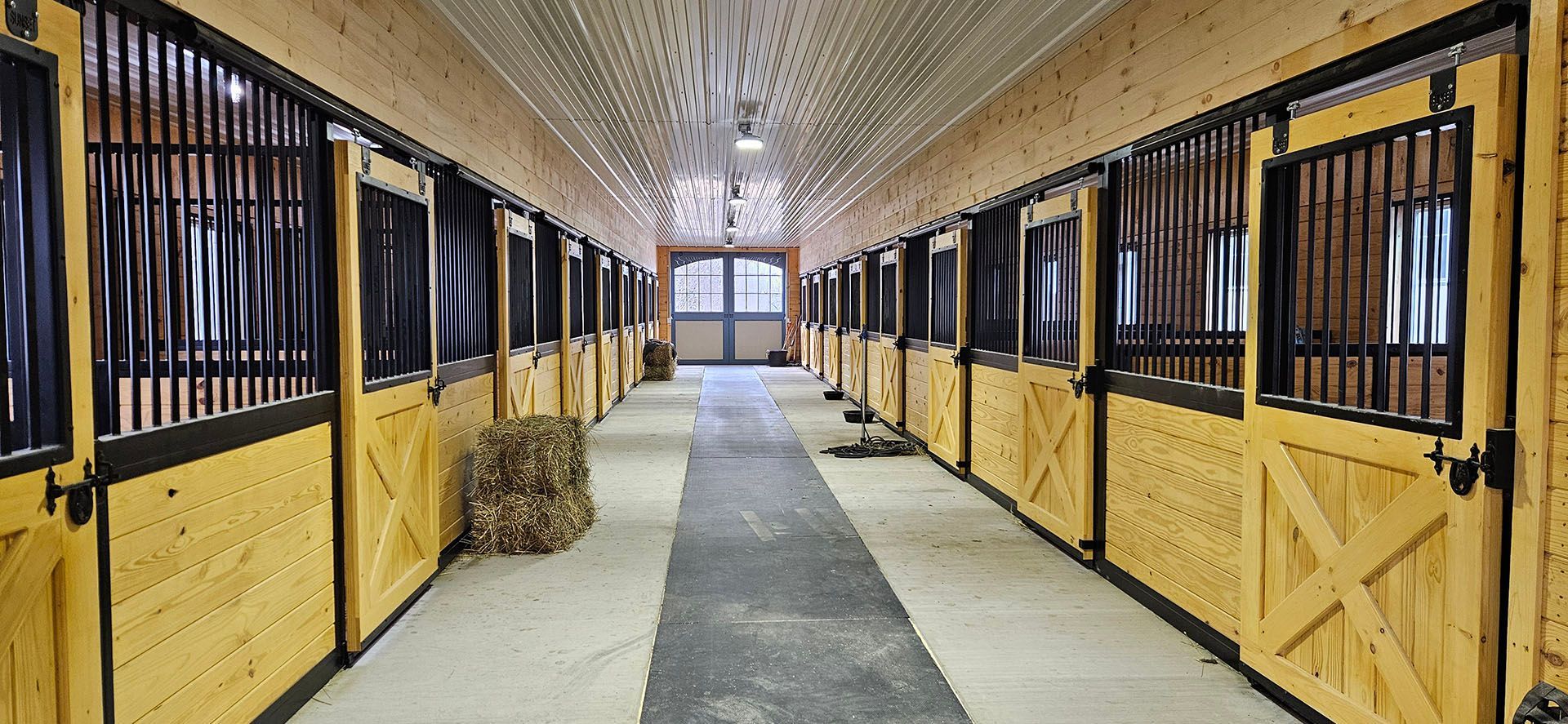 A long hallway filled with rows of wooden horse stables.
