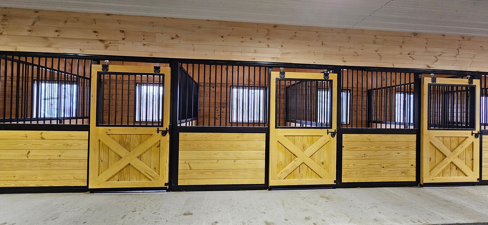 A row of wooden horse stalls with yellow doors in a barn.